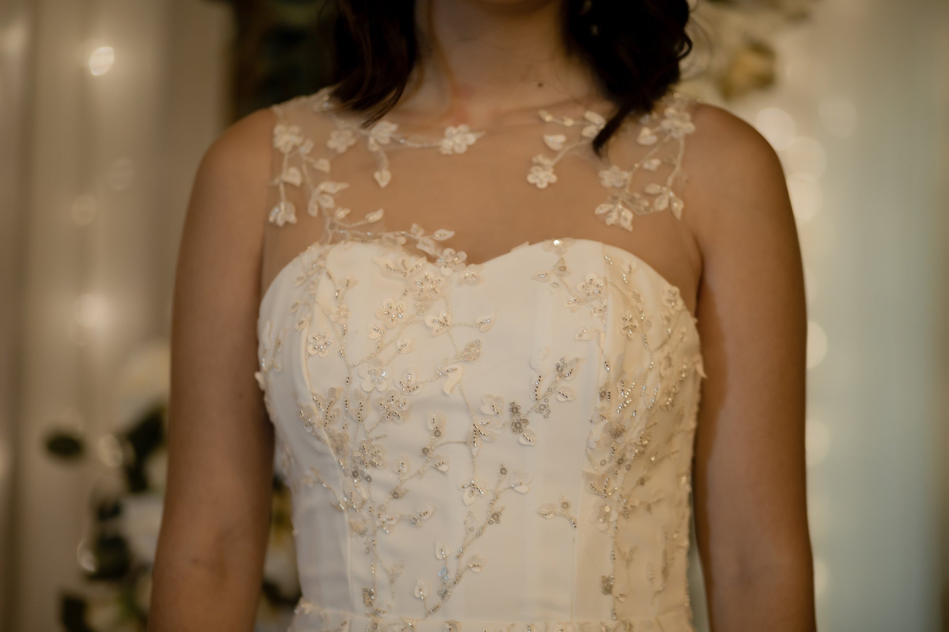 An upclose shot of the just the front bodice of the lorien gown on a model, the lace looks as if its growing and is hand placed over illusion straps to look like its floating on the skin