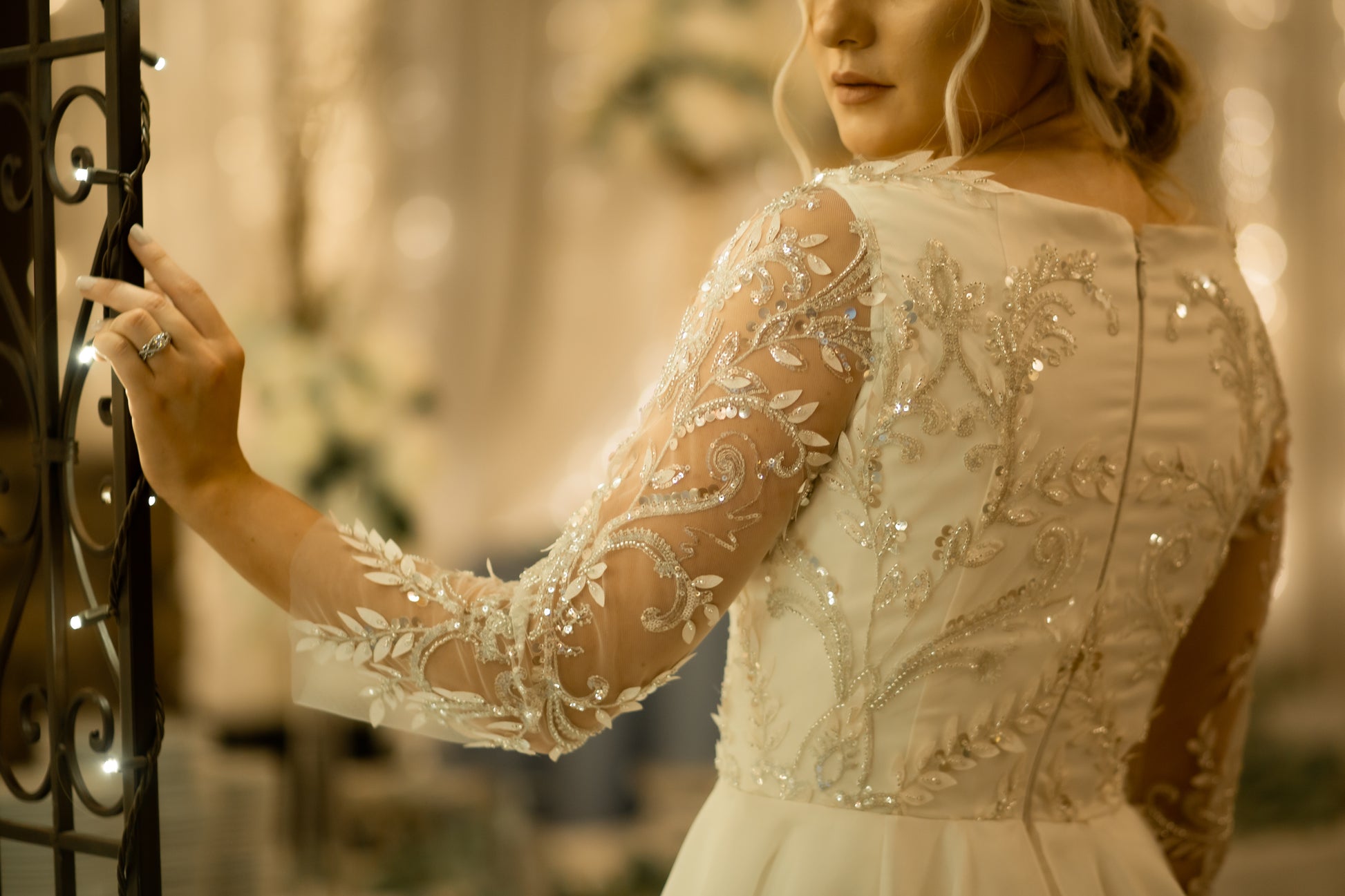 A focused close up of the back bodice and sleeve of the Theodora gown and the lace pattern on it.