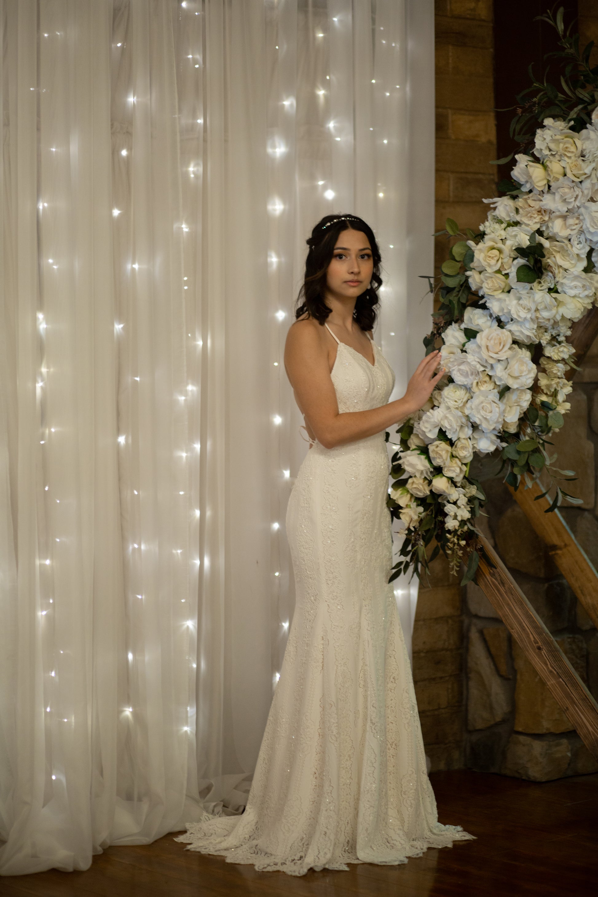 The 1970's inspired gown, willoughby, on a bride from the side view, it shows it fitted through hips and flaring at mid-thigh into a soft lower skirt.