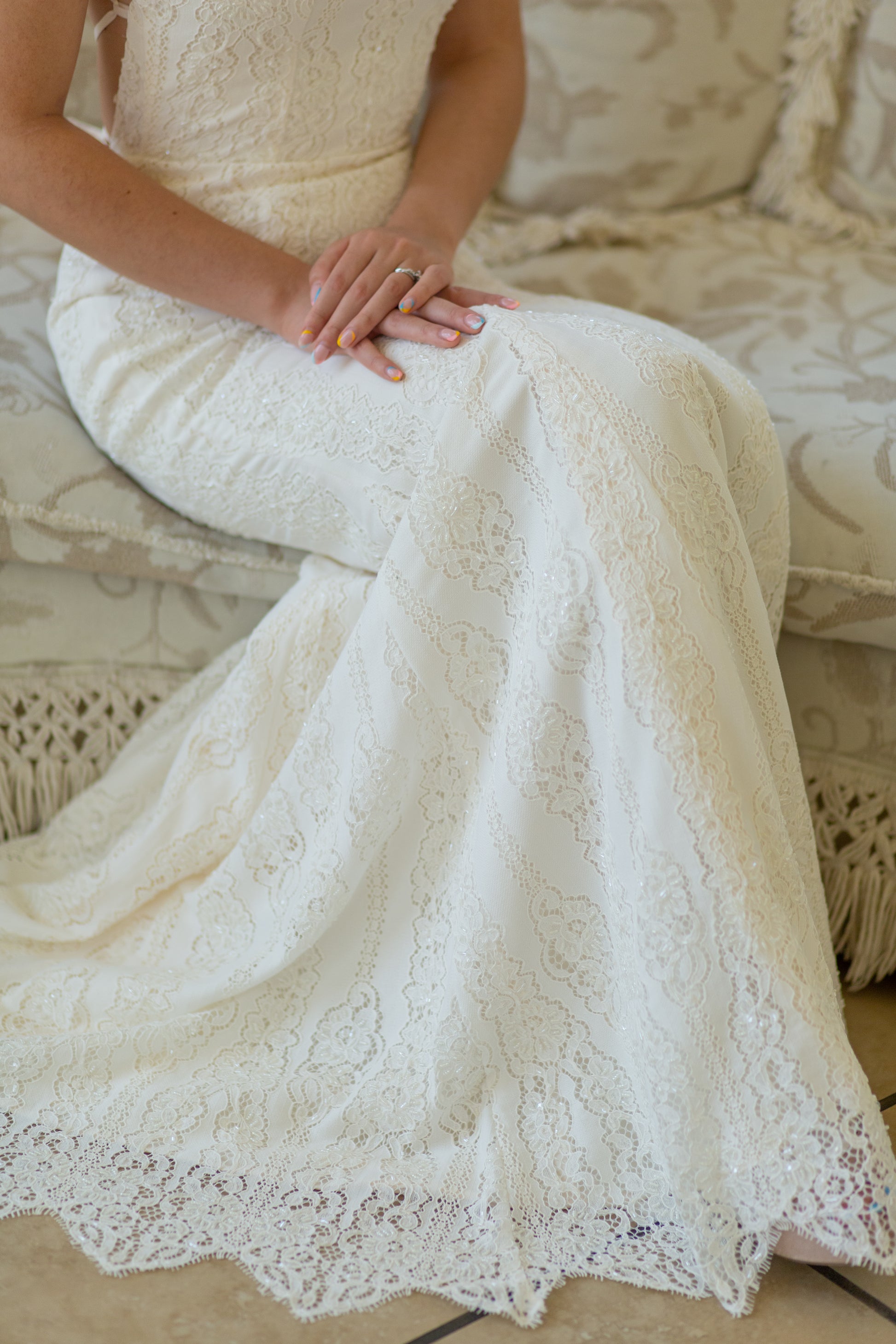 A close up of the lace pattern and lower skirt of the Willoughby gown; the unique scallop is shown off on the floor while the vertical lines of the lace are visable above.