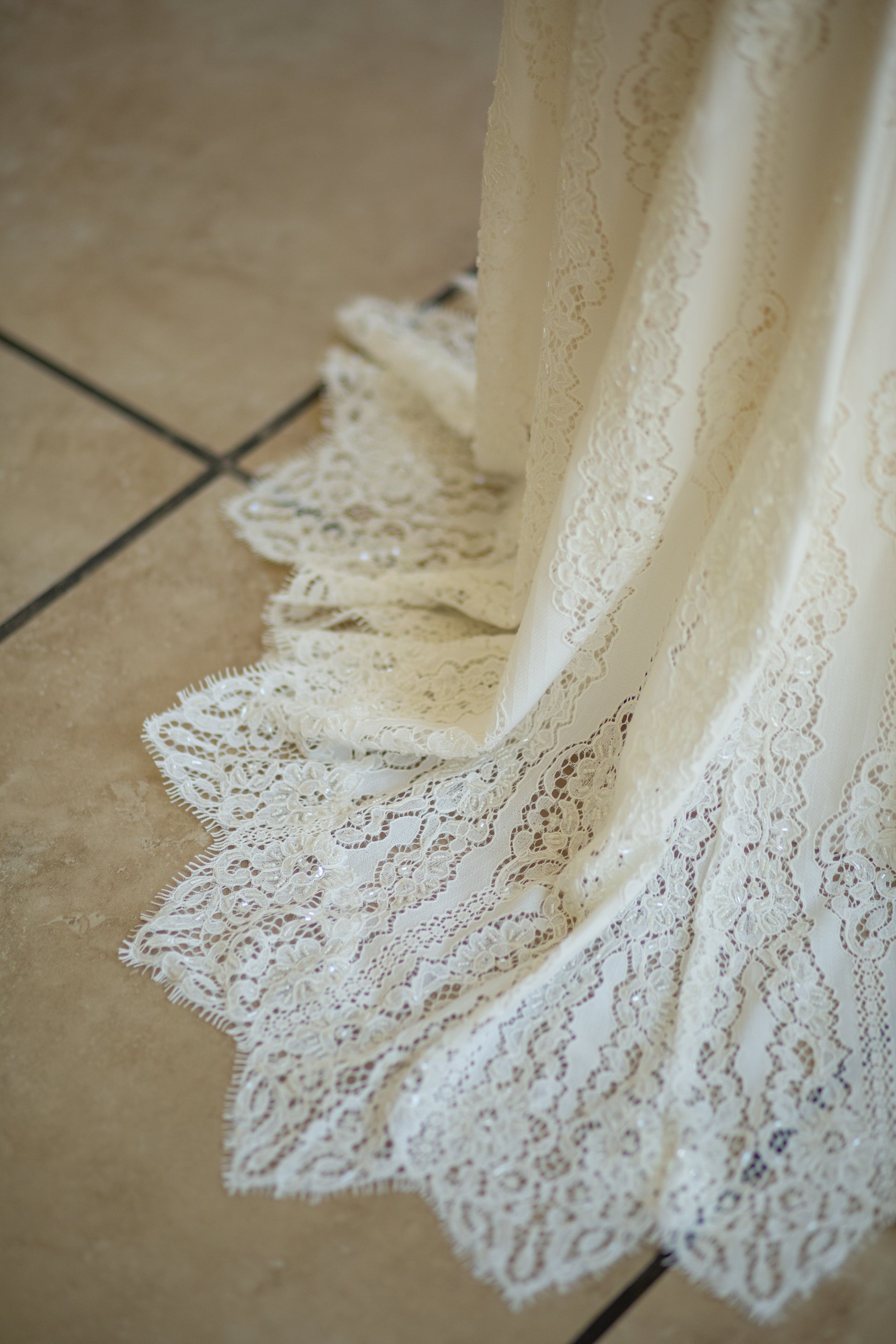 A close up detail shot of the  Irregular scalloped hem with eyelash lace trim on the Willoughby wedding gown.