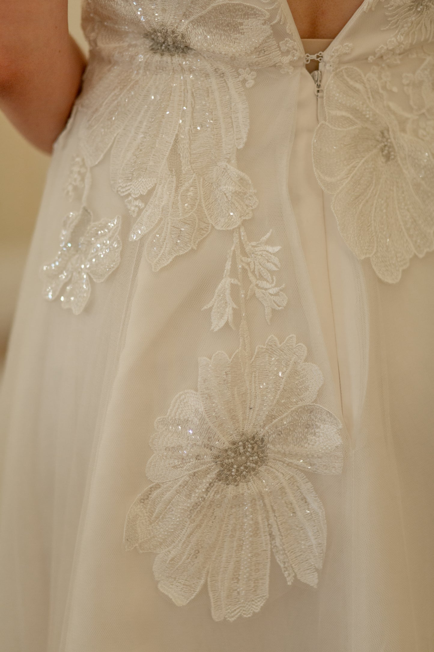 A close up of the floral lace on poppy; the lace is trailing down asymetrically into the tulle skirt.