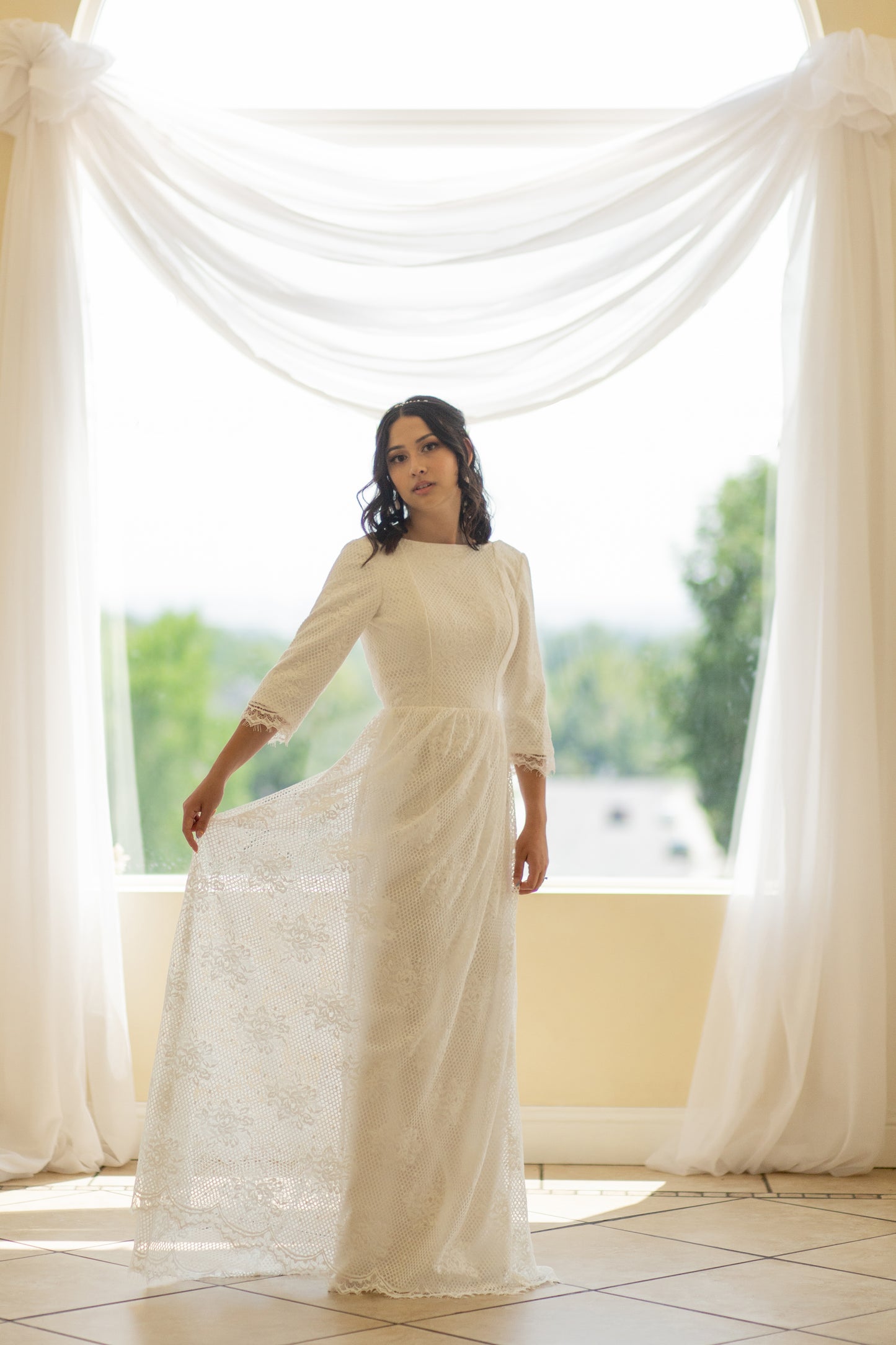 Bride twirling gently in the Avabelle gown, soft lace skirt flaring slightly to reveal graceful movement and dimension in the rose-patterned lace overlay.