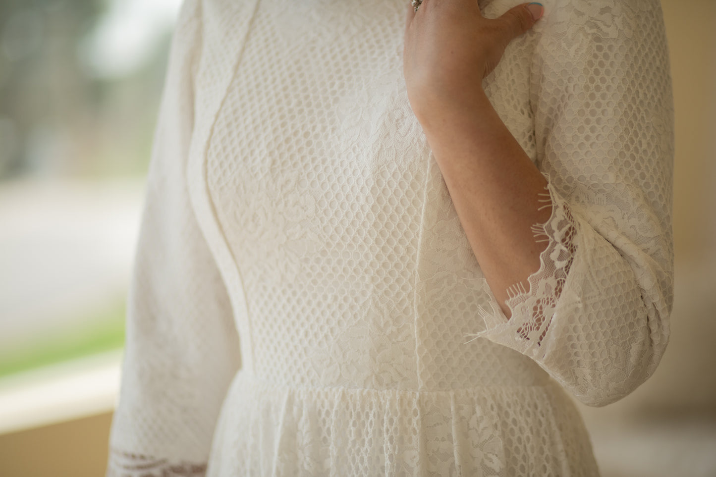Detailed close-up of the Avabelle gown’s lace bodice and three-quarter-length sleeves, revealing the intricate rose lace, cording, and eyelash trim along the scalloped edges.