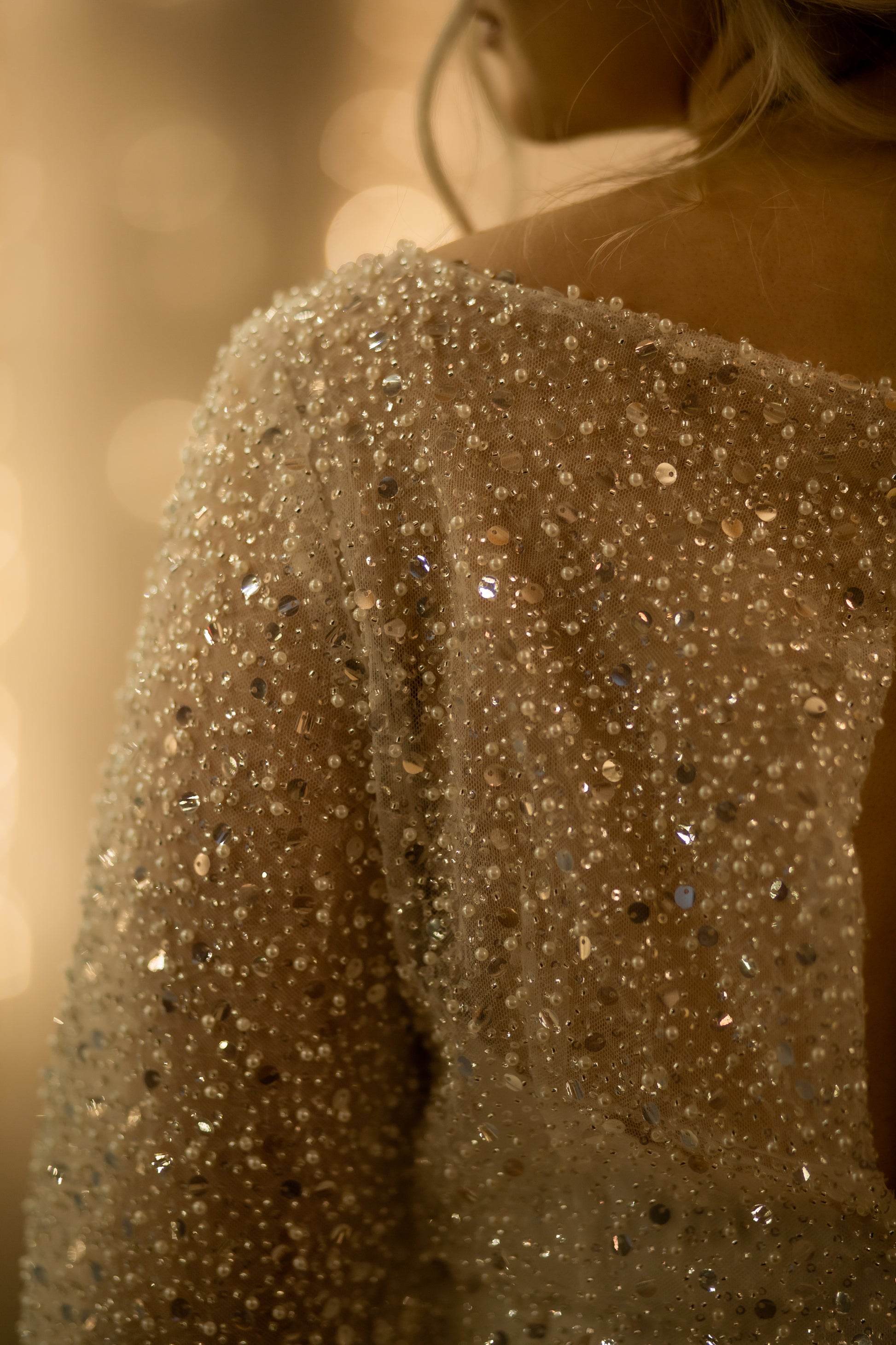 Close-up of sheer sleeve showing pearl, sequin, and bead embellishments.