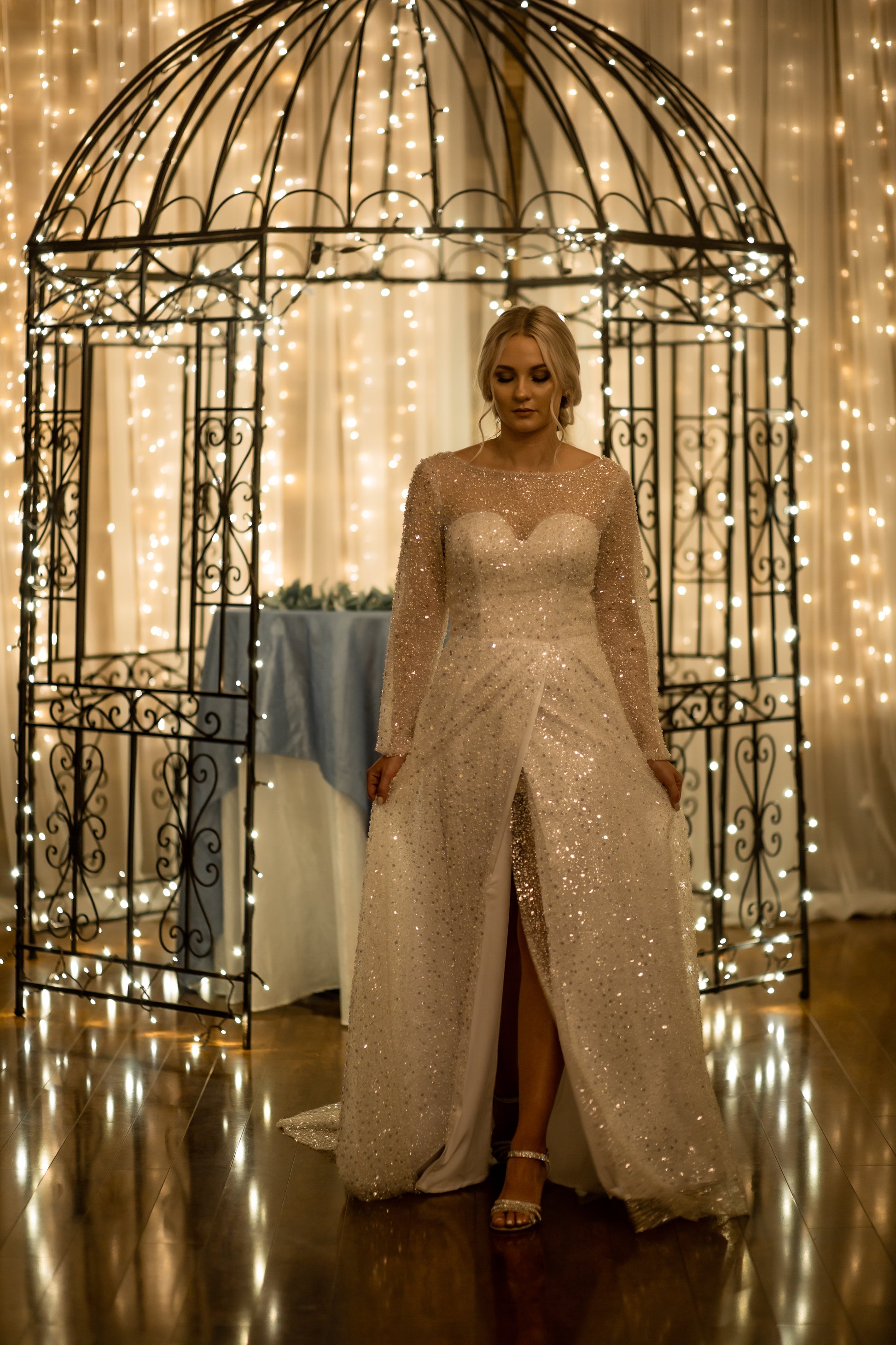 Walking shot capturing subtle A-line silhouette and adjustable wrap slit with model holding the sides of the skirt out to the sides.
