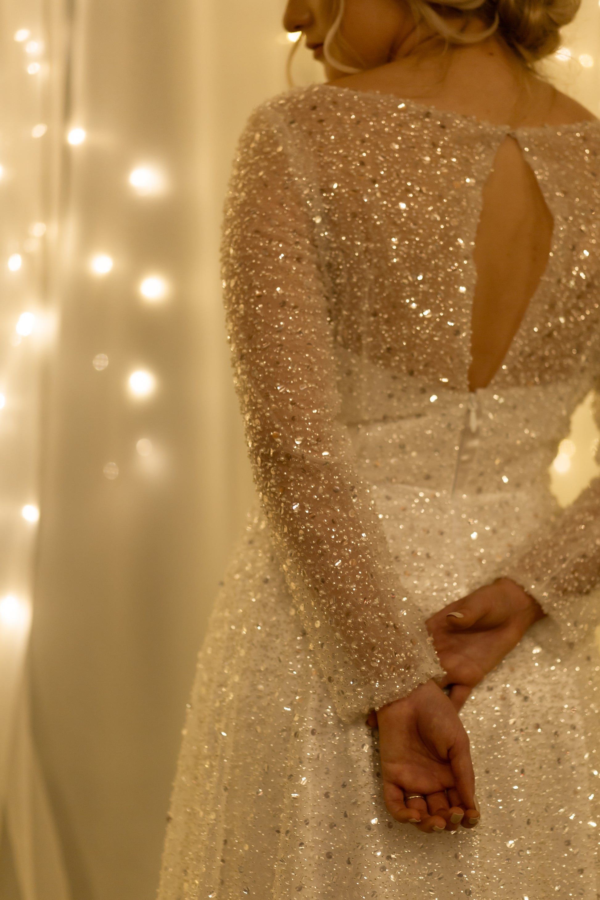 Bride turned, highlighting back closure, sleeves, and illusion neckline.