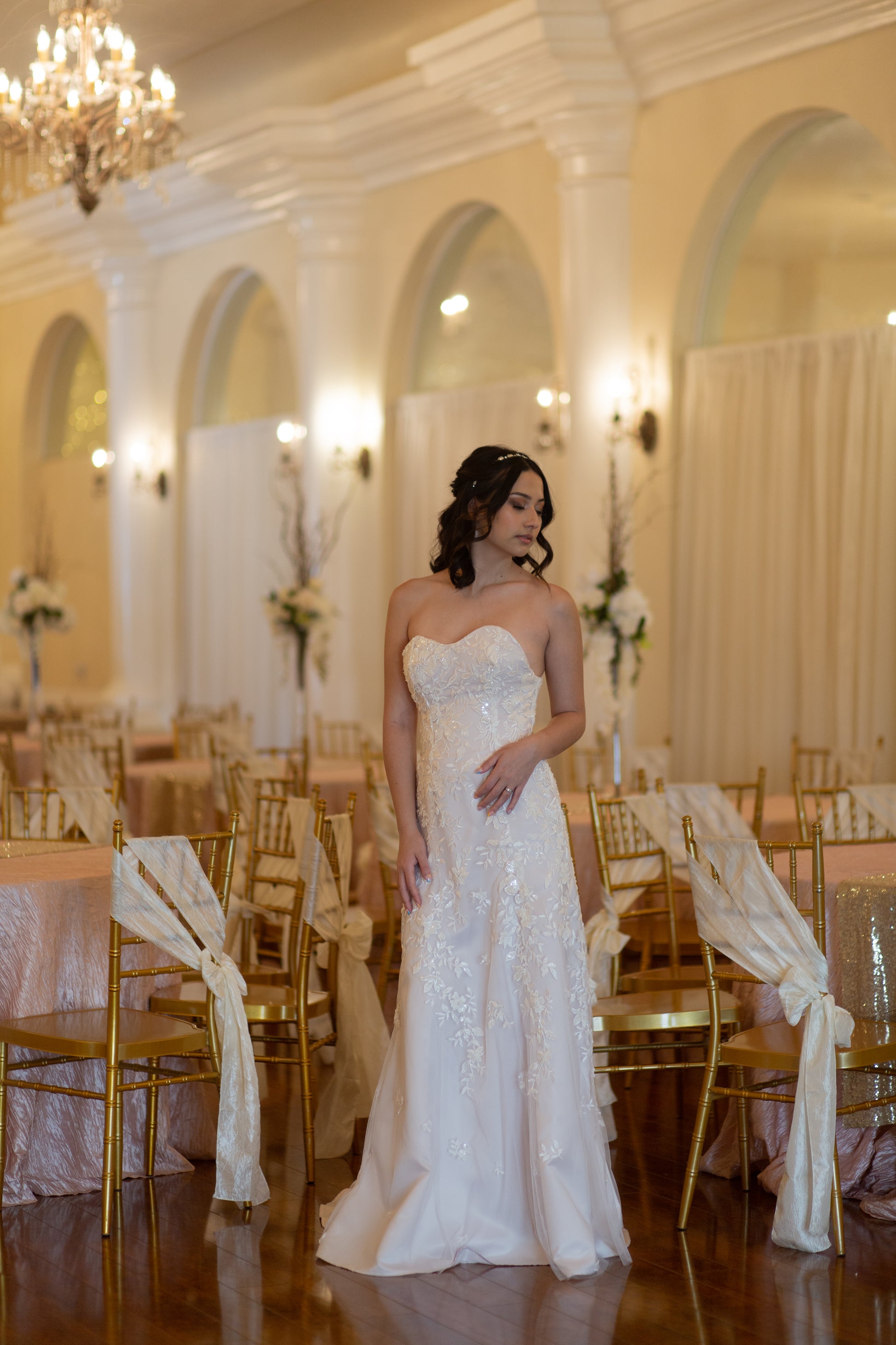 A full length shot of the Sawyer bridal gown, worn by a bride, the strapless gown has the lace becoming sparser toward the hem for delicate effect.