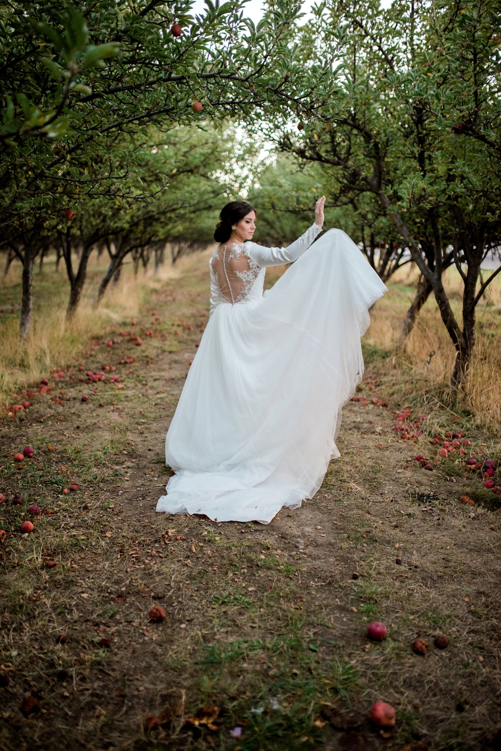 Bride standing in the Ava gown, soft tulle skirt gathered and tossed in the air, highlighting the gown’s classic and graceful design.