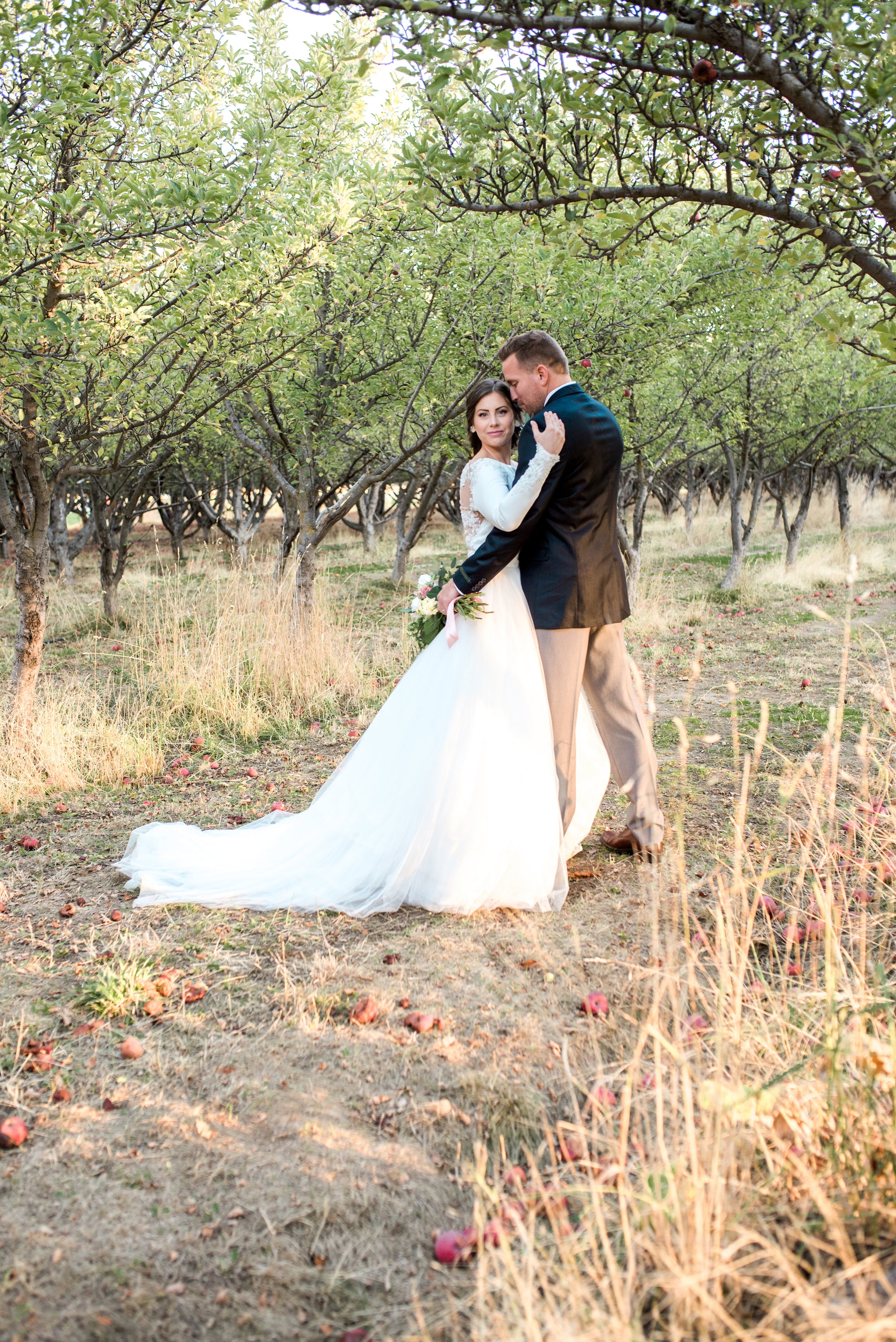 Side view of the Ava gown showing structured satin sleeve, nipped waist, and voluminous tulle skirt with long train.
