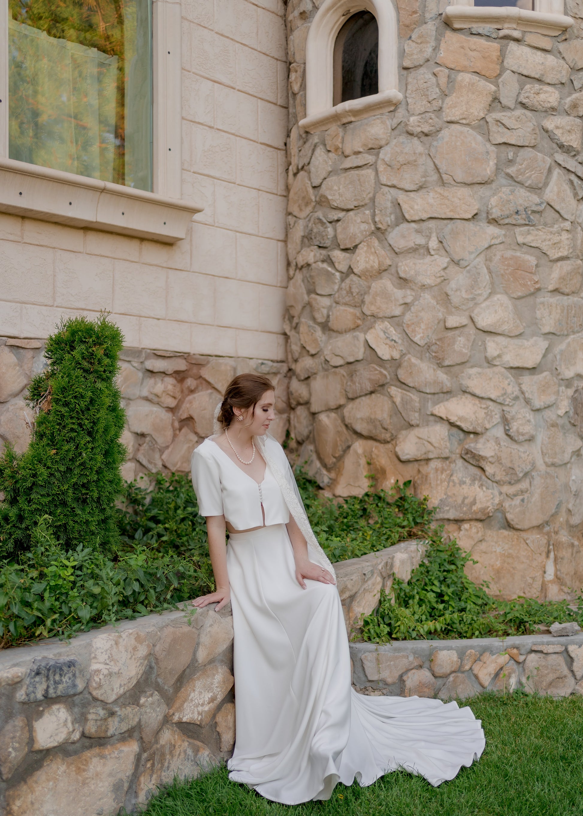 Bride seated while wearing the Cassie set, showing the curved neckline and short sleeves of the top with the flattering fit of the skirt.