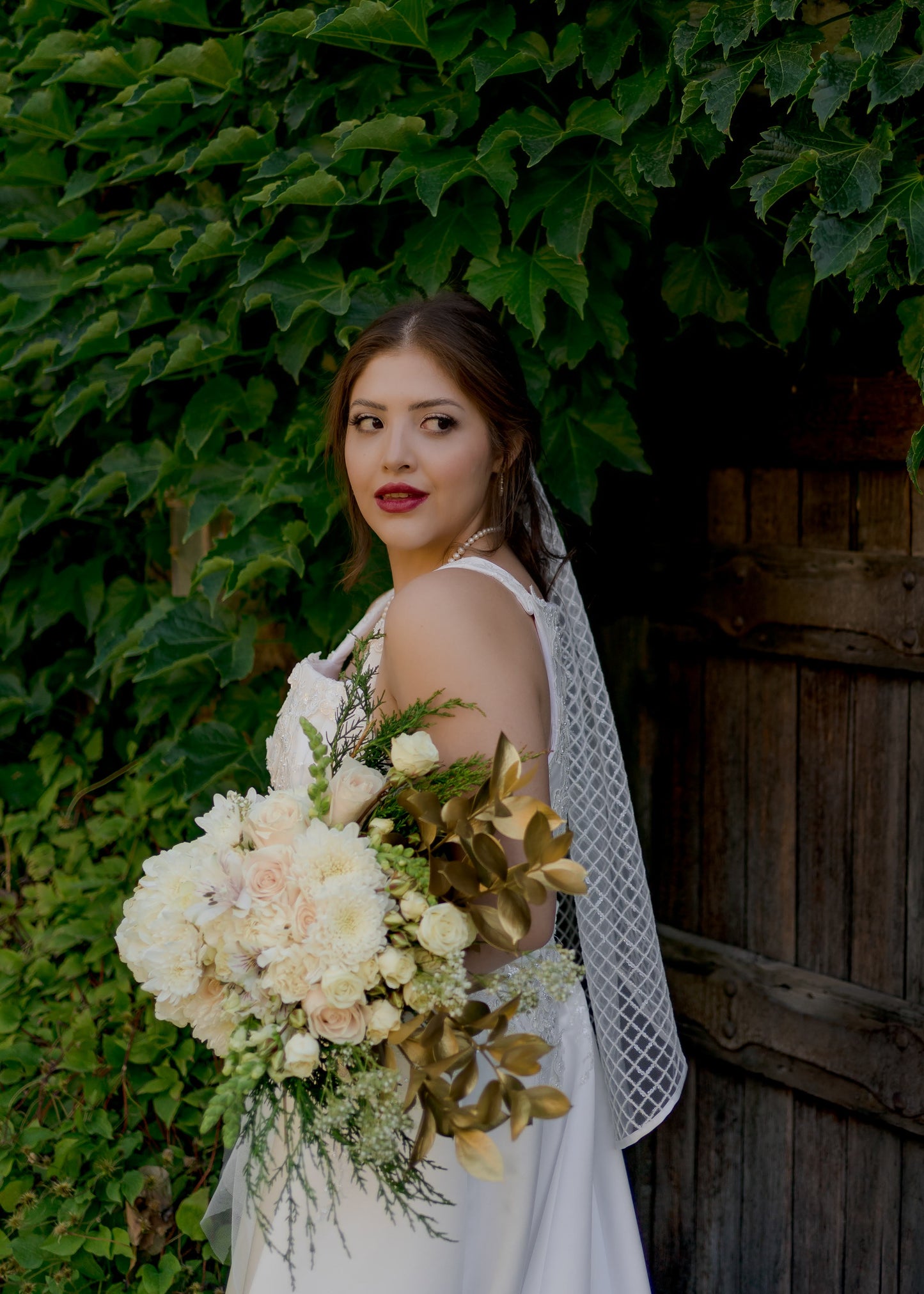 A photo of a bride looking over her shoulder, she wears the gloria veil with diamond sequins and a ribbon edge in a fingertip length.