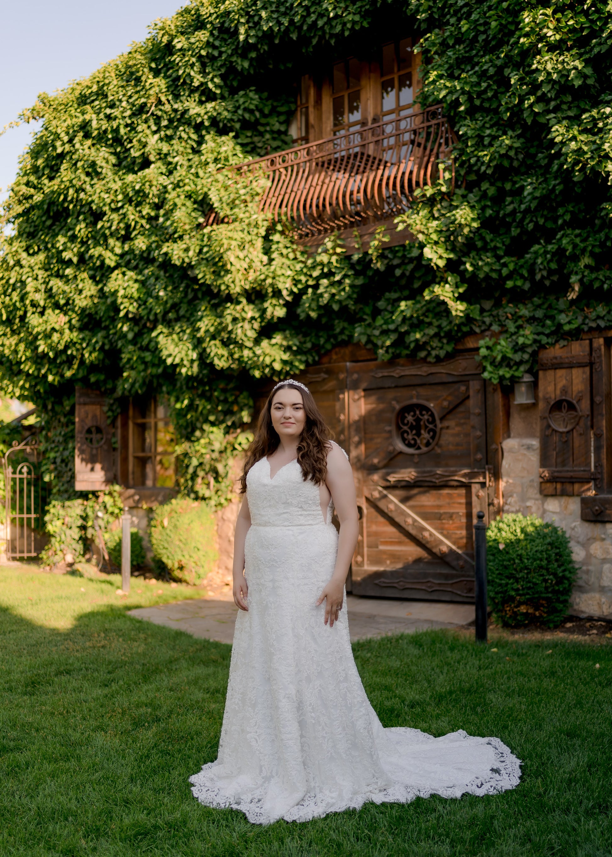 A ¾ view of the Margaret gown in ivory on a size 18 model. The Eighteen-inch scalloped train extends back beyond the trumpet silhouette.