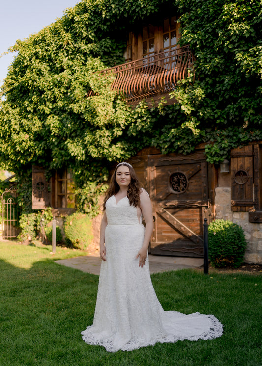 A ¾ view of the Margaret gown in ivory on a size 18 model. The Eighteen-inch scalloped train extends back beyond the trumpet silhouette.