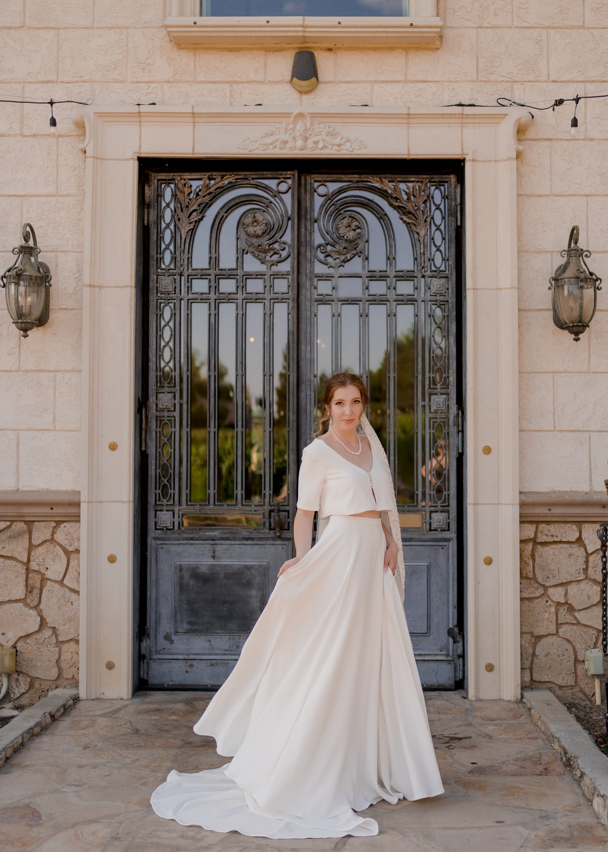 Bride wearing the Cassie two-piece wedding set outdoors, with the cropped top and flowing A-line skirt creating an elegant, modern silhouette