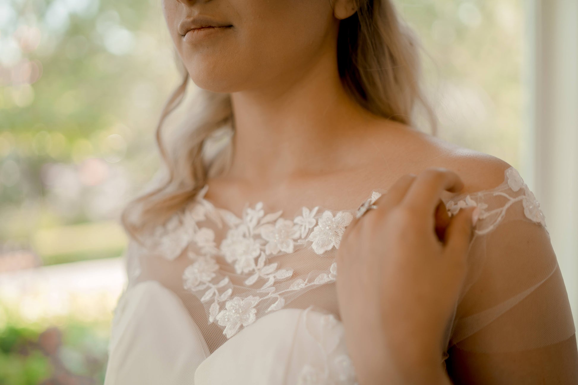 Detailed close-up of the bardot neckline on the model, showcasing the natural lace edge, delicate off-shoulder tulle sleeves, and the softly structured sweetheart satin bodice beneath.