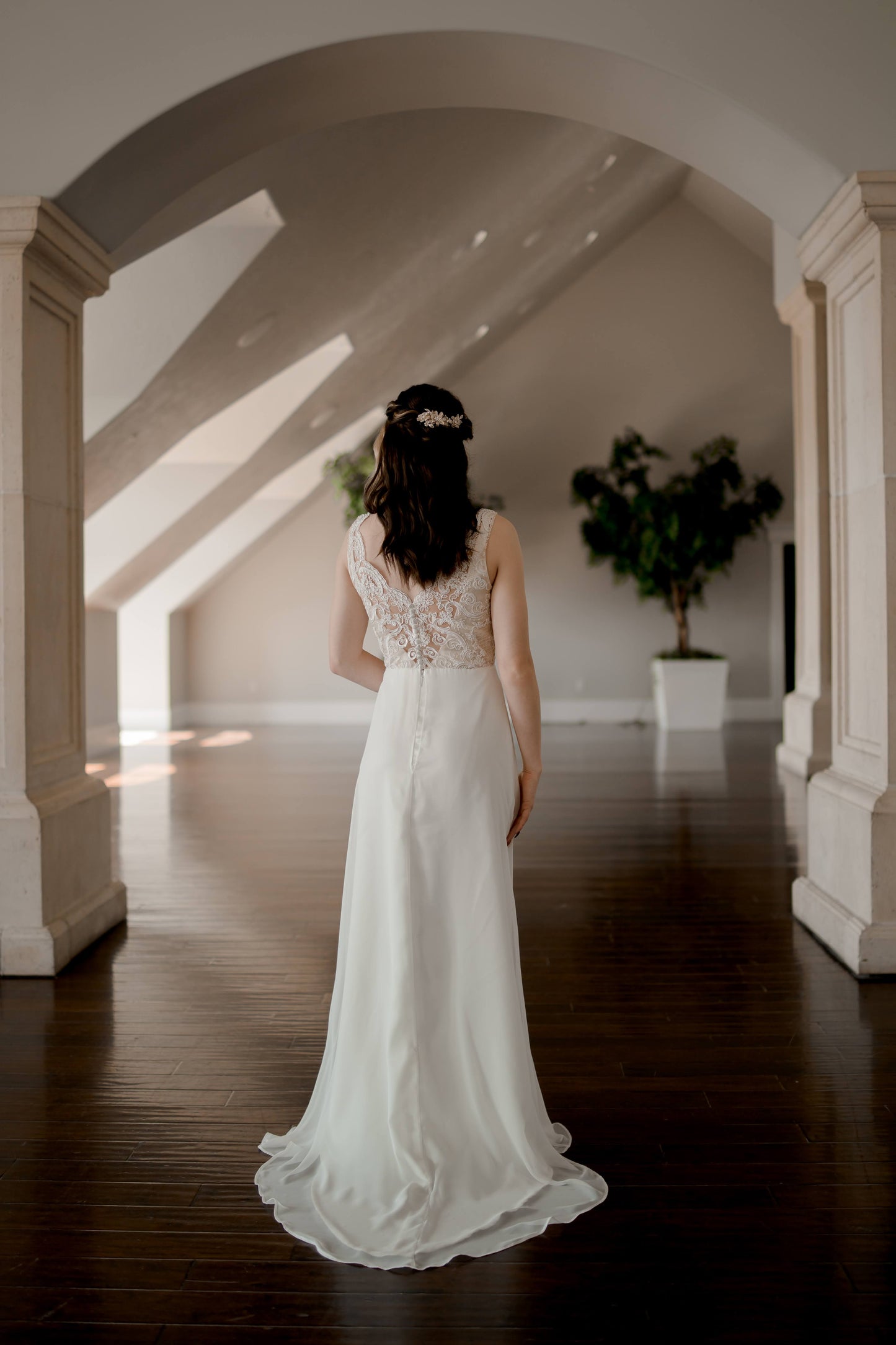 A full length back shot of the Winifred gown in Ivory on a bride with the flowy chiffon and satin train and the lace textured bodice.