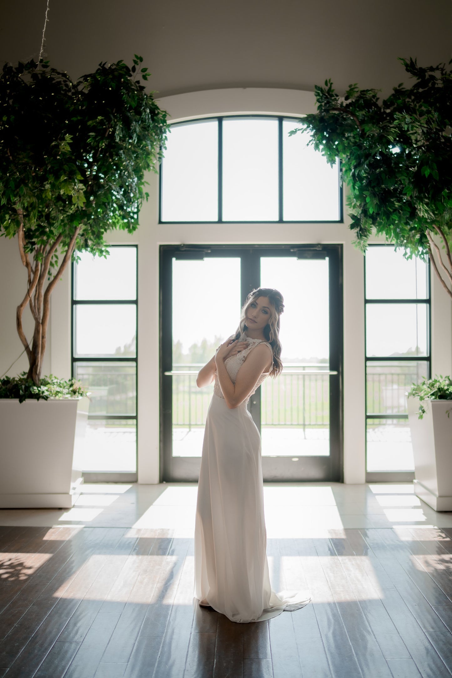 A back lite profile photo of the winifred gown on a bride showcasing the way the structured bodice fits and how the lightweight satin and chiffon skirt flows delicately over curves.