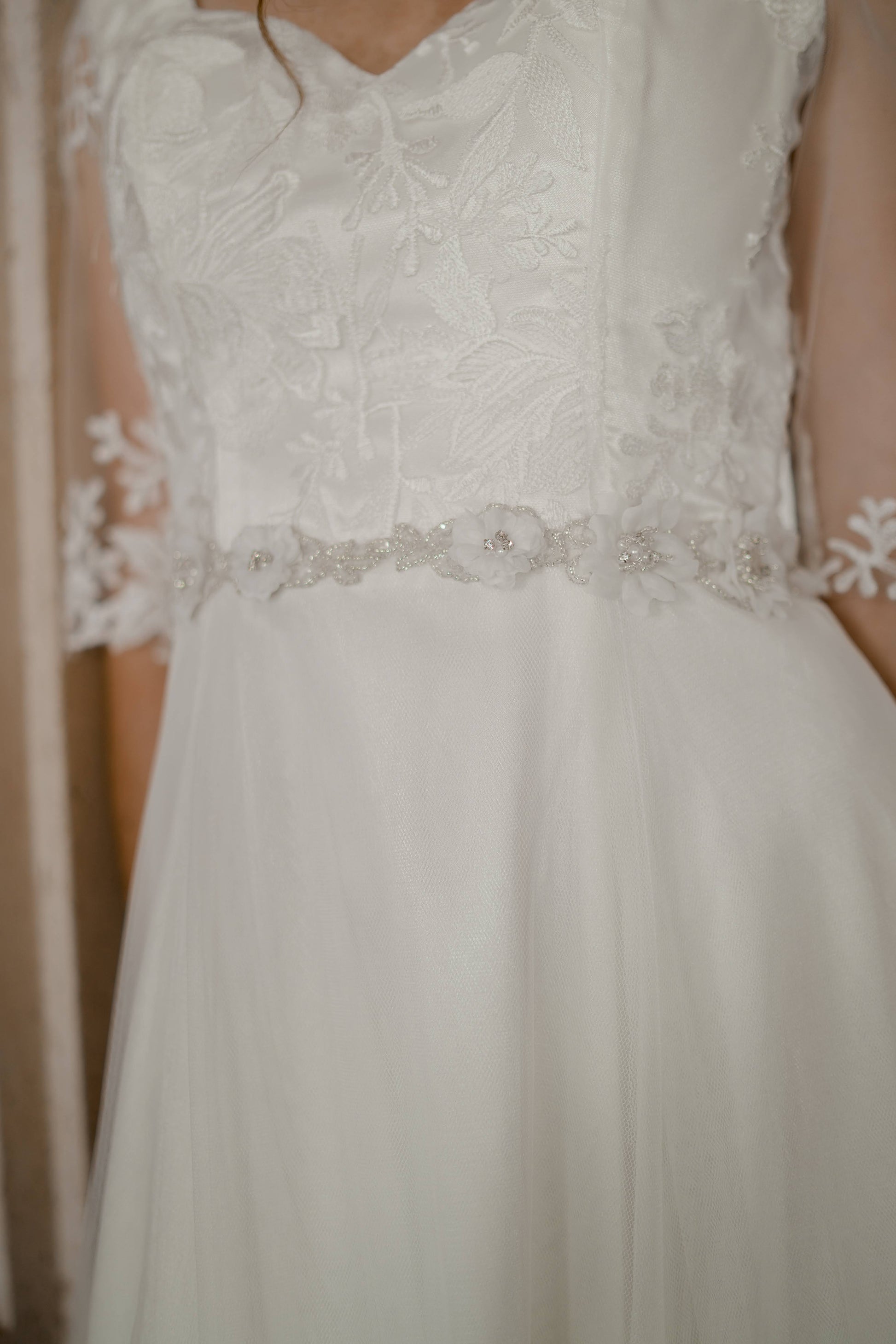 A close up image of the front ¾ angle of the heidi bridal sash with 3d flowers and beading styled on a wedding gown.