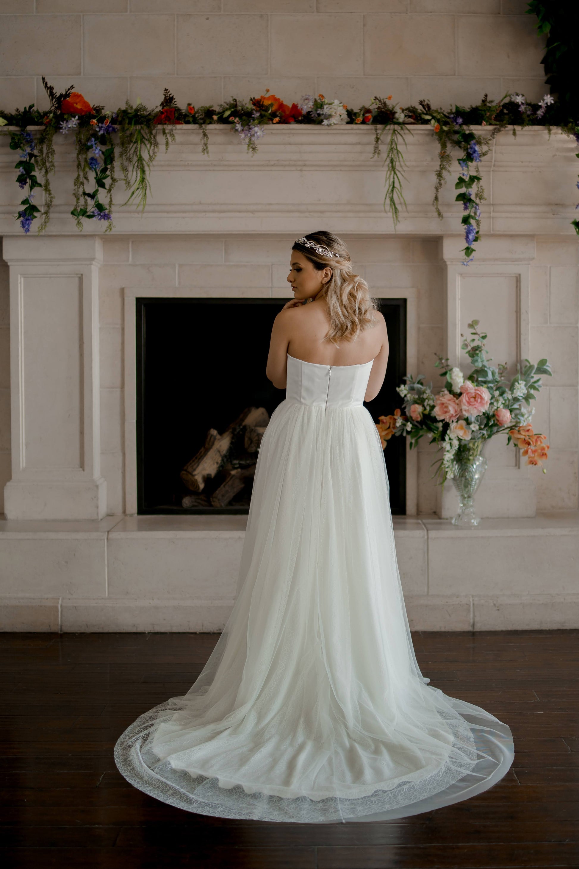 Back view of the Beatrice wedding dress on a model, highlighting the layered tulle and lace train that extends gracefully behind.
