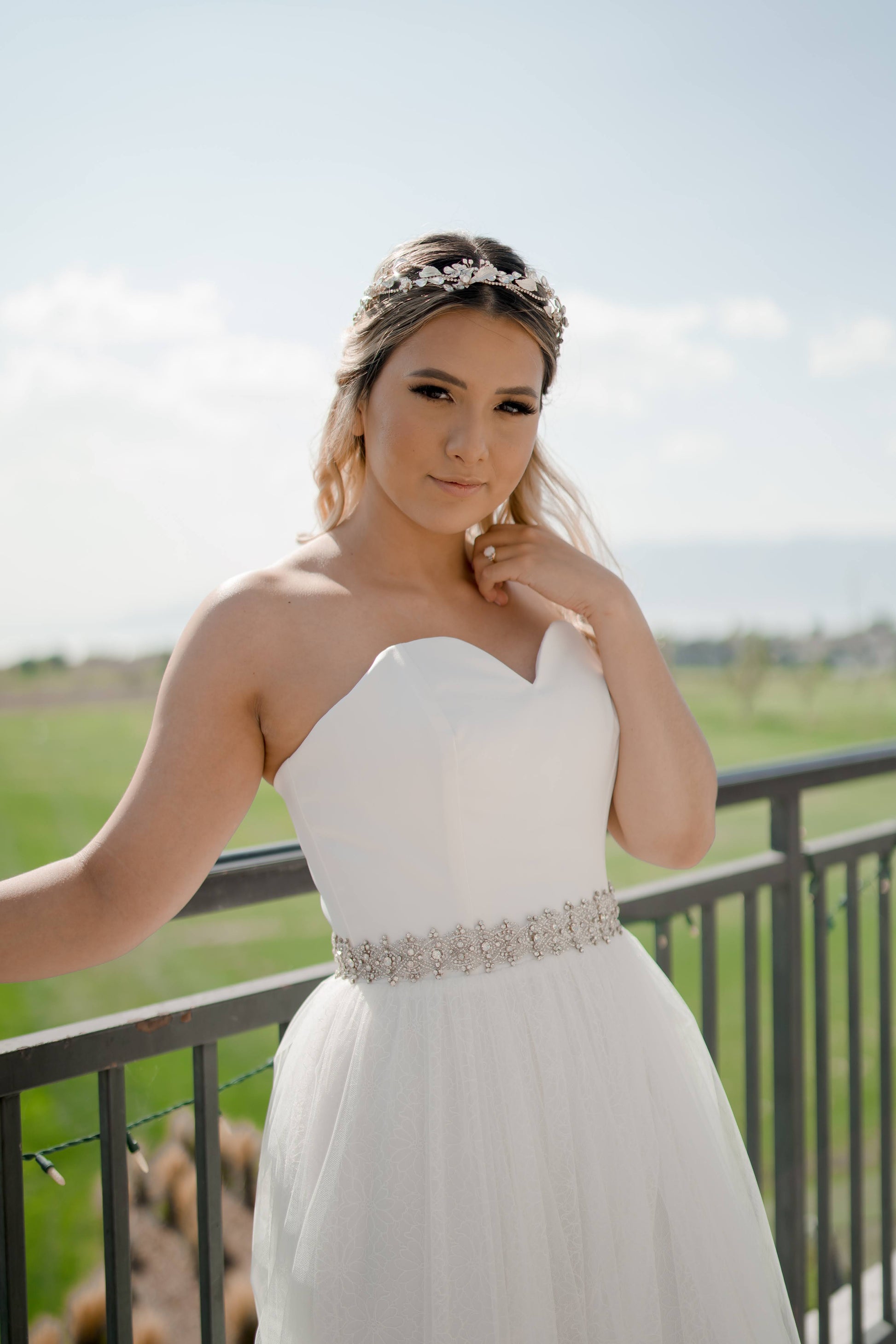 Close-up of the bride wearing a the Beatrice gown, showing soft gathered tulle overlaid with daisy lace for a delicate textured effect, the sasha belt, and a simple satin bodice.