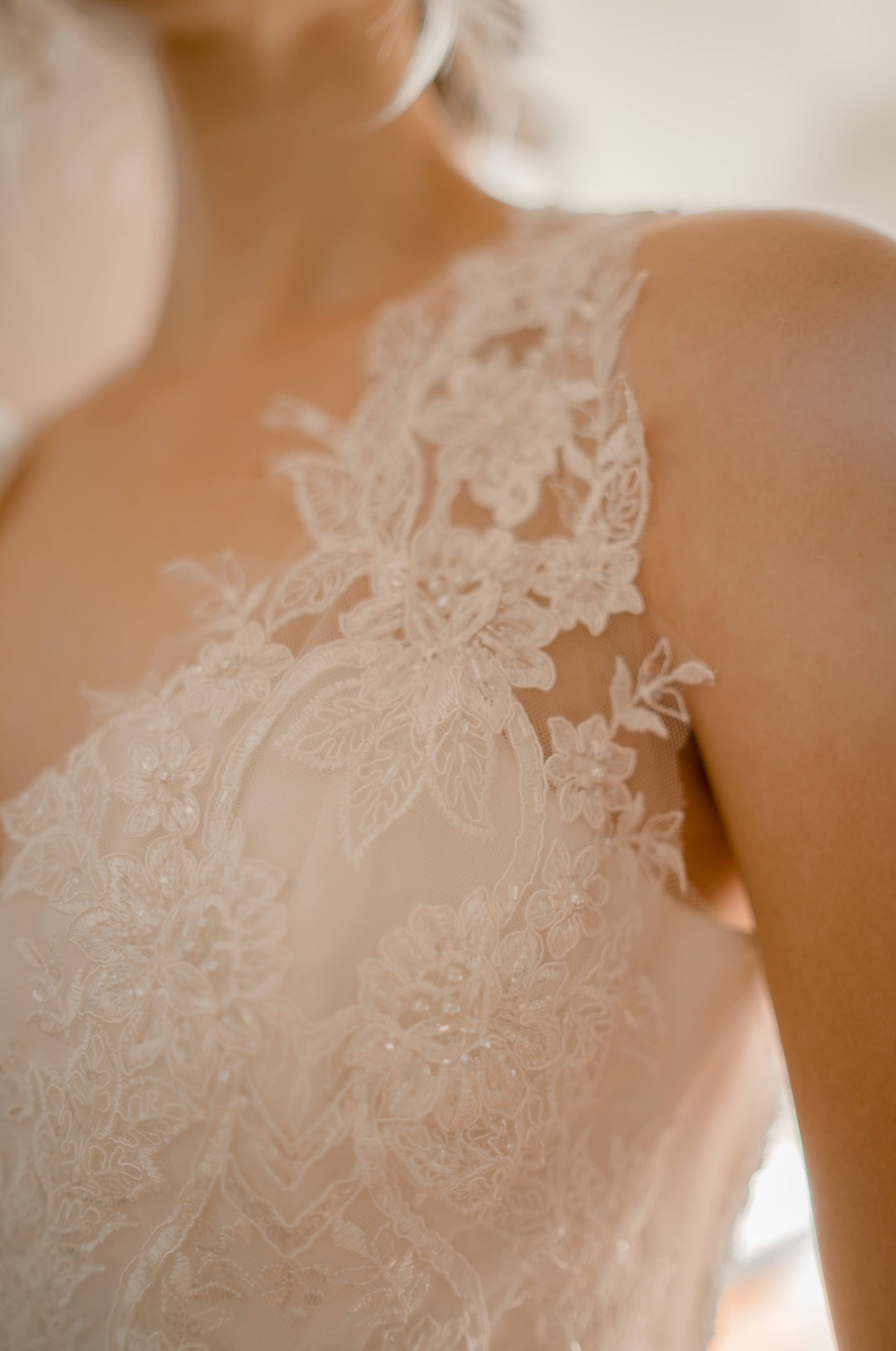 close up shot of the marie gown's bust and illusion strap; the lace is beaded and features a floral pattern stretching up over the satin sweetheart neckline.