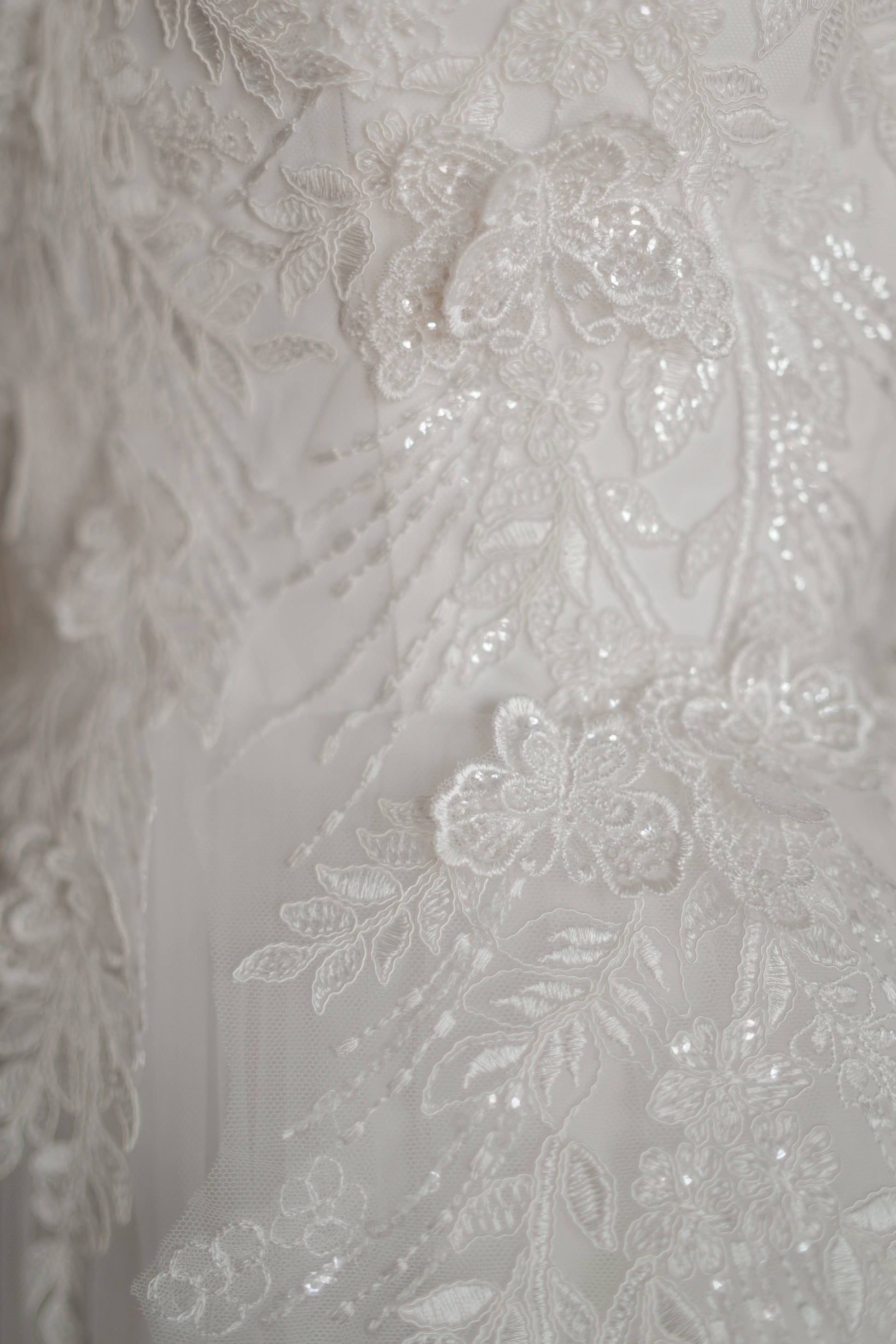 Detailed view of floral and butterfly lace across satin bodice.