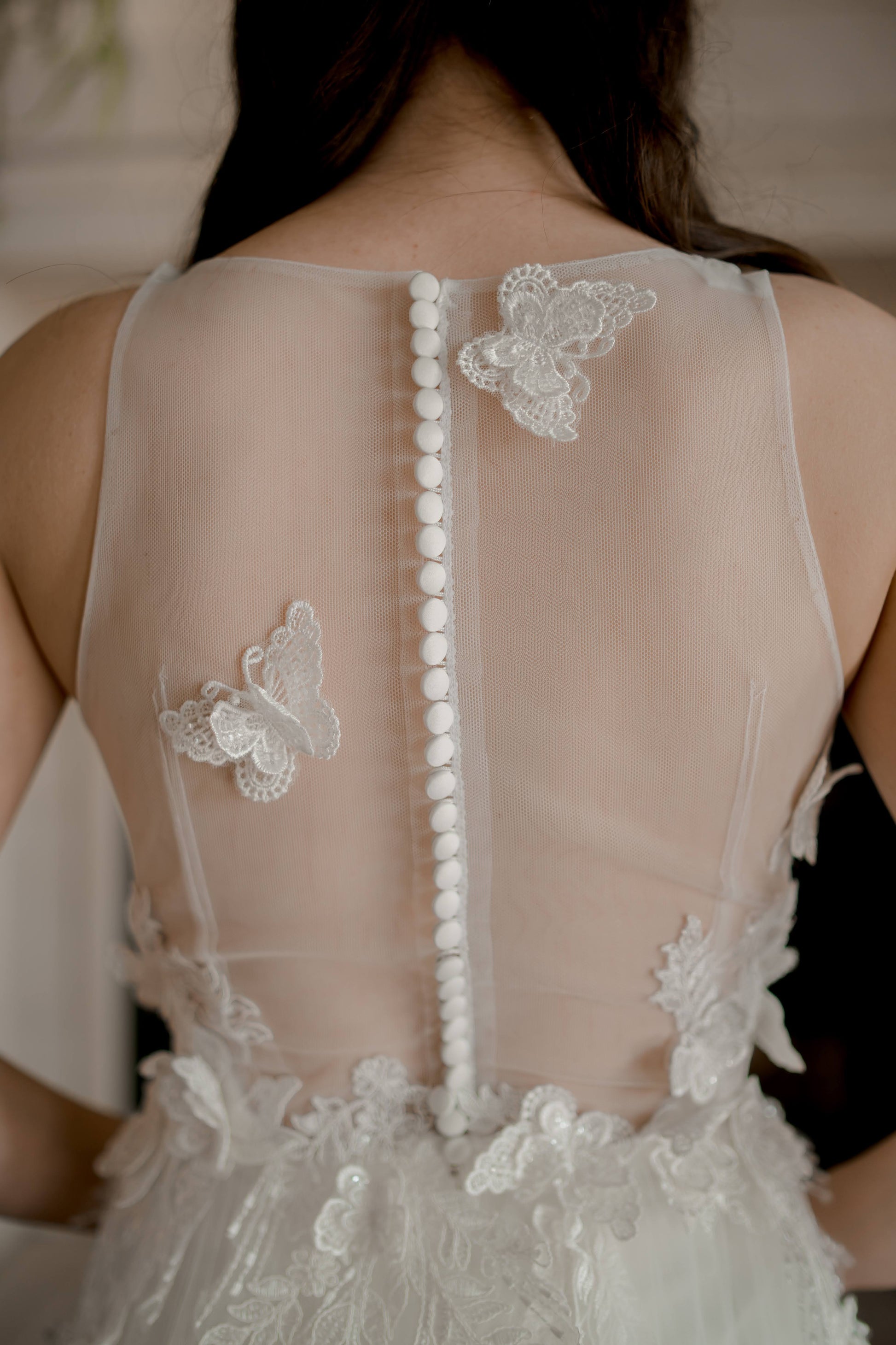 Hand-sewn butterfly on illusion tulle near back neckline.