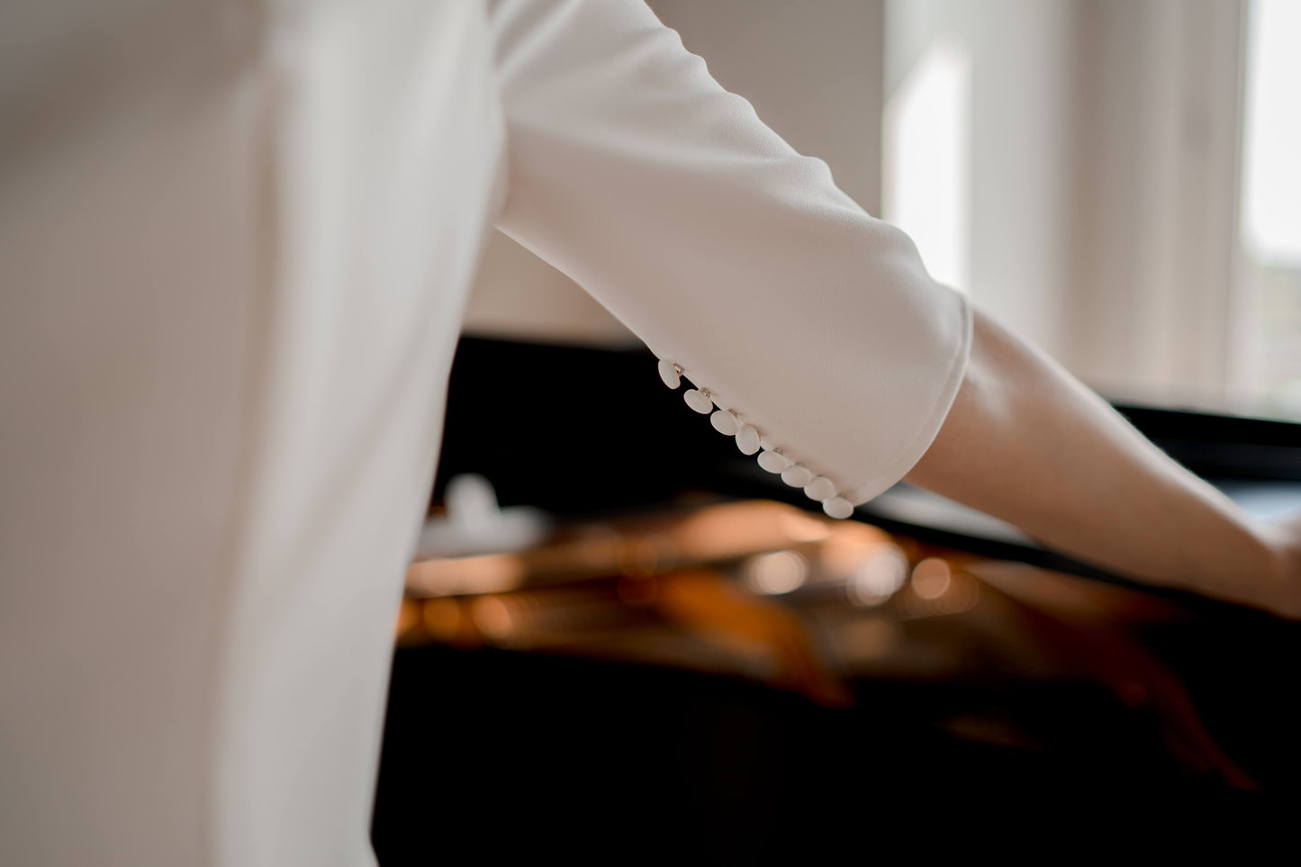 An upclose shot of the Elbow-length sleeves with subtle seams and minimalist cut of the wendy gown; covered buttons are placed on the underneath seam of the sleeve.