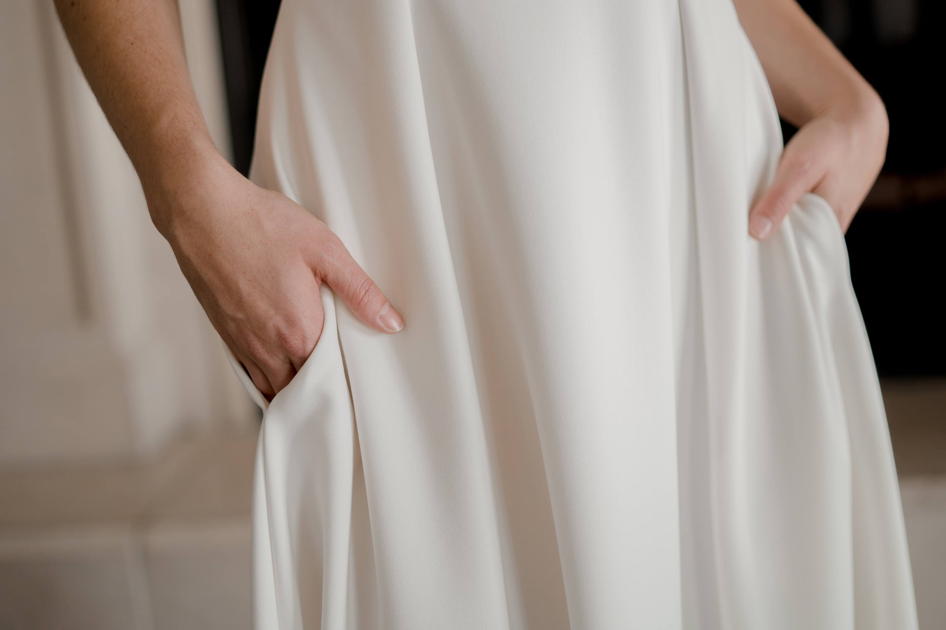 An upclose photo of the skirt witha bride wearing the Wendy gown, her hands are in the  hidden pockets, showcasing functionality.