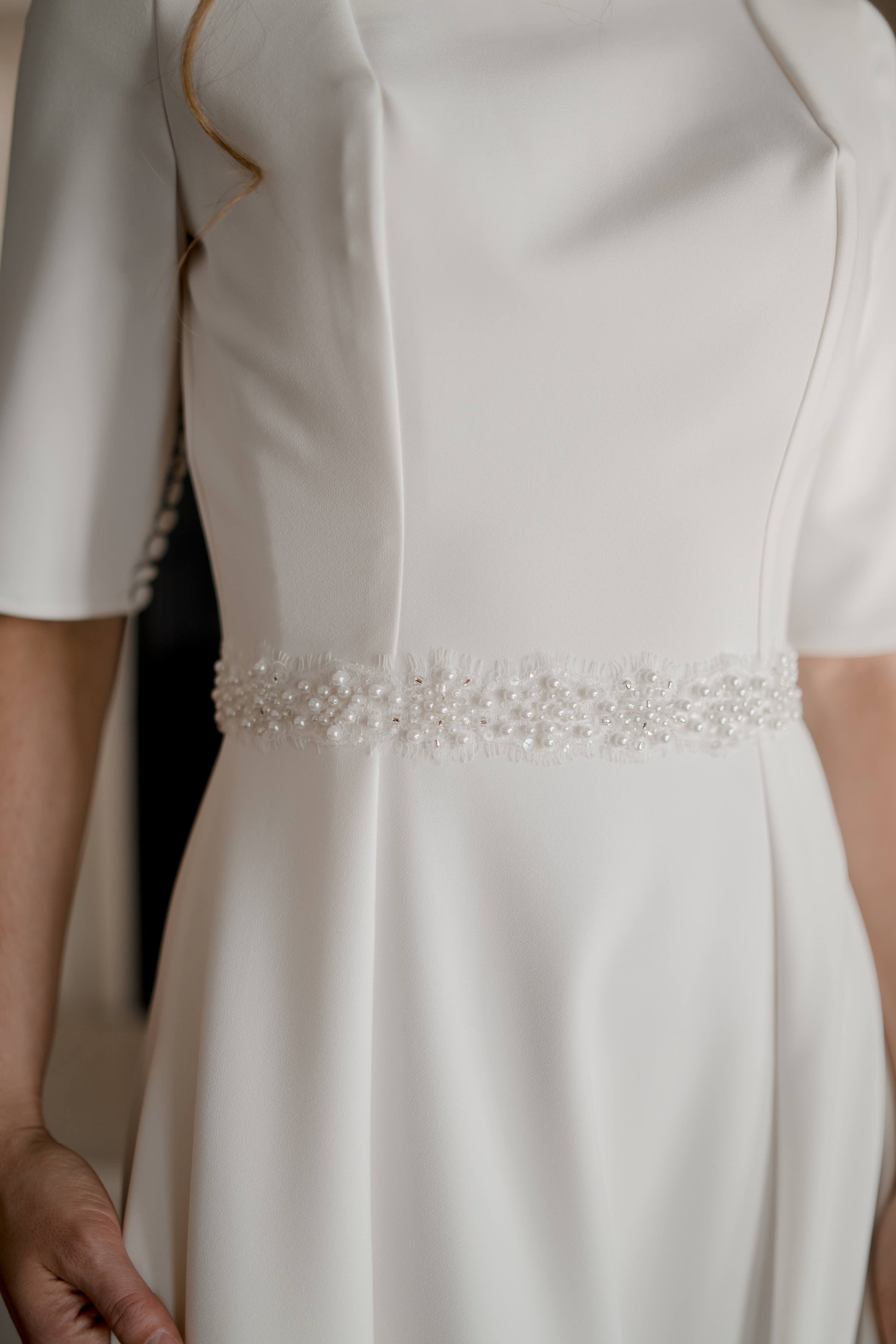 A close up of the Millie belt on top of our wendy gown, the pearls are prominent while the eyelash details and lace base are  more of a textured accent.