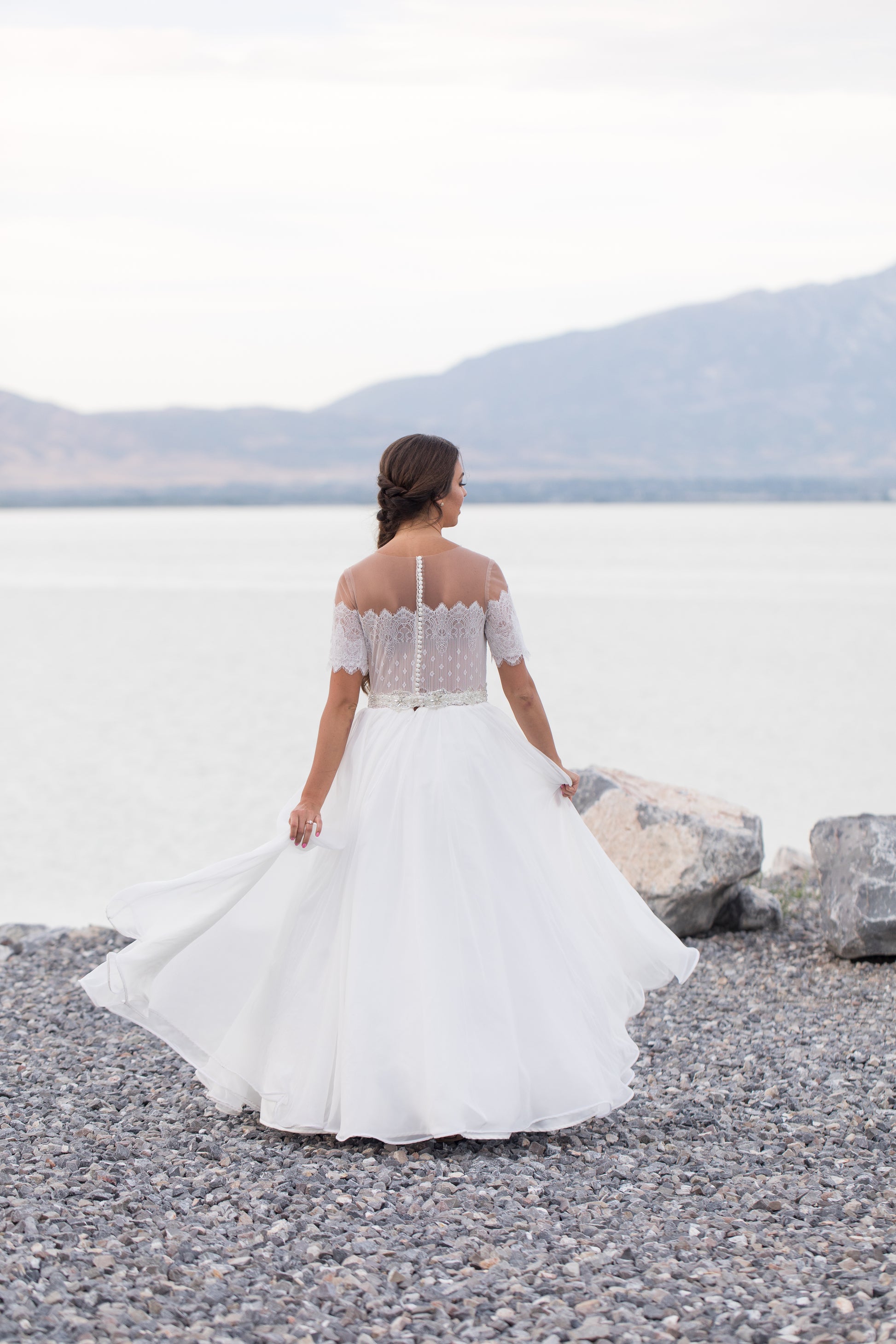 The ronelle gown on a bride; she is spinning  showing off the Flowing chiffon skirt in motion, highlighting volume and softness