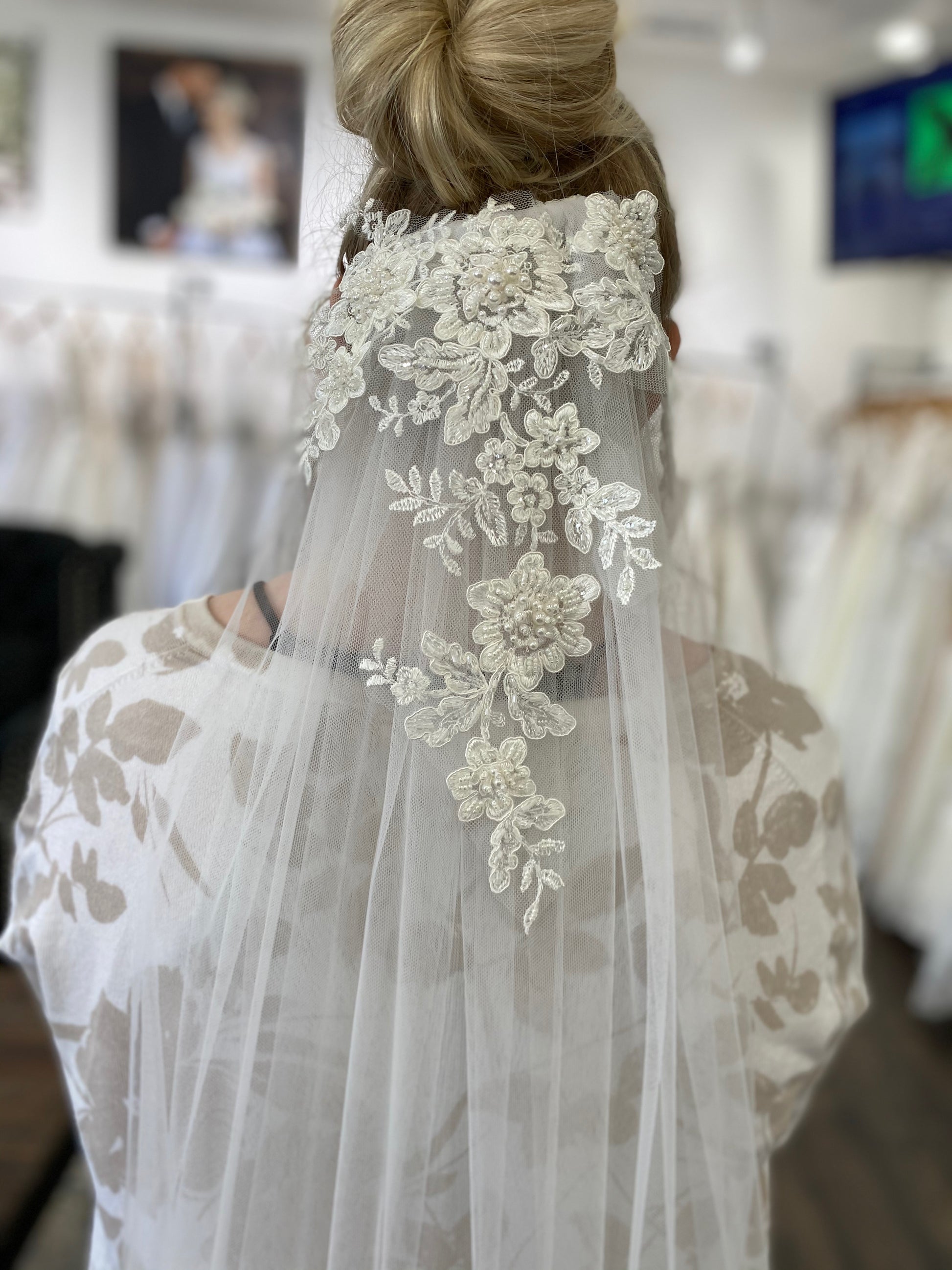 A close up of the sharon veil in a womans hair; the veil has pale Ivory cascading with lace at crown and is positioned under her updo.