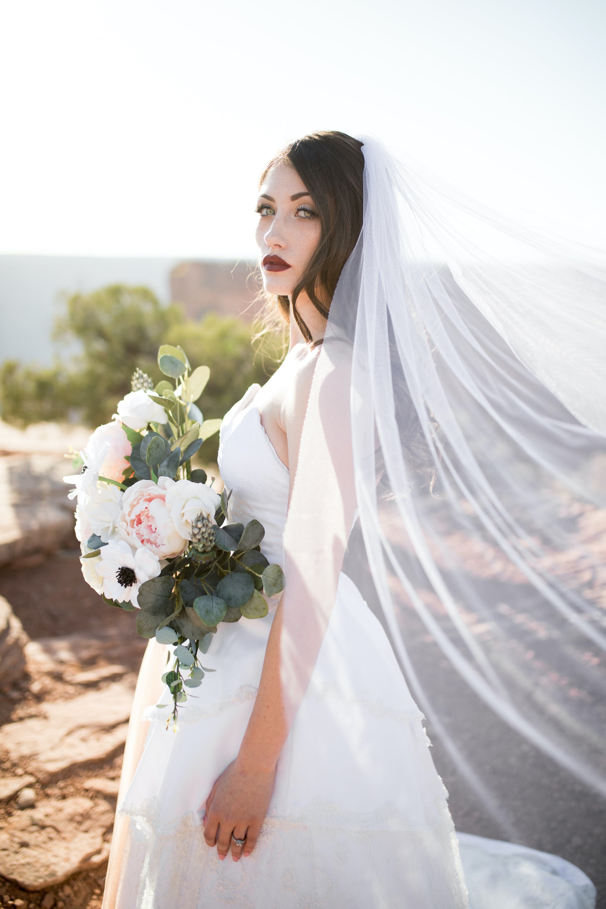 A bride wears a ball gown, and a bridal veil. The bridal veil is the jane, made in oft tulle this wedding veil is extra light weight and is caught in the breeze in the image. 