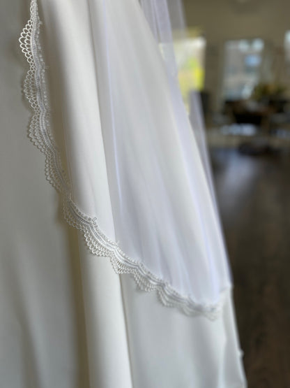A close up of the curved edge of the brennan bridal veil; the veil is laying against the bottom of the Wendy crepe skirt. The soft tulle base lays close to the body with little volumne. 