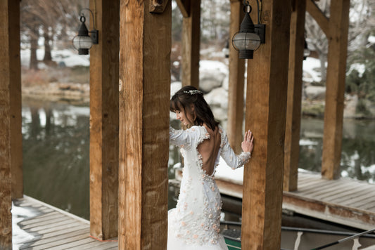 ¾ angled view of the lydia gown on a bride, showing the Mermaid silhouette gown with scoop back and long sleeves. The gown is shown here in satin, the crepe version would just be more matte. 