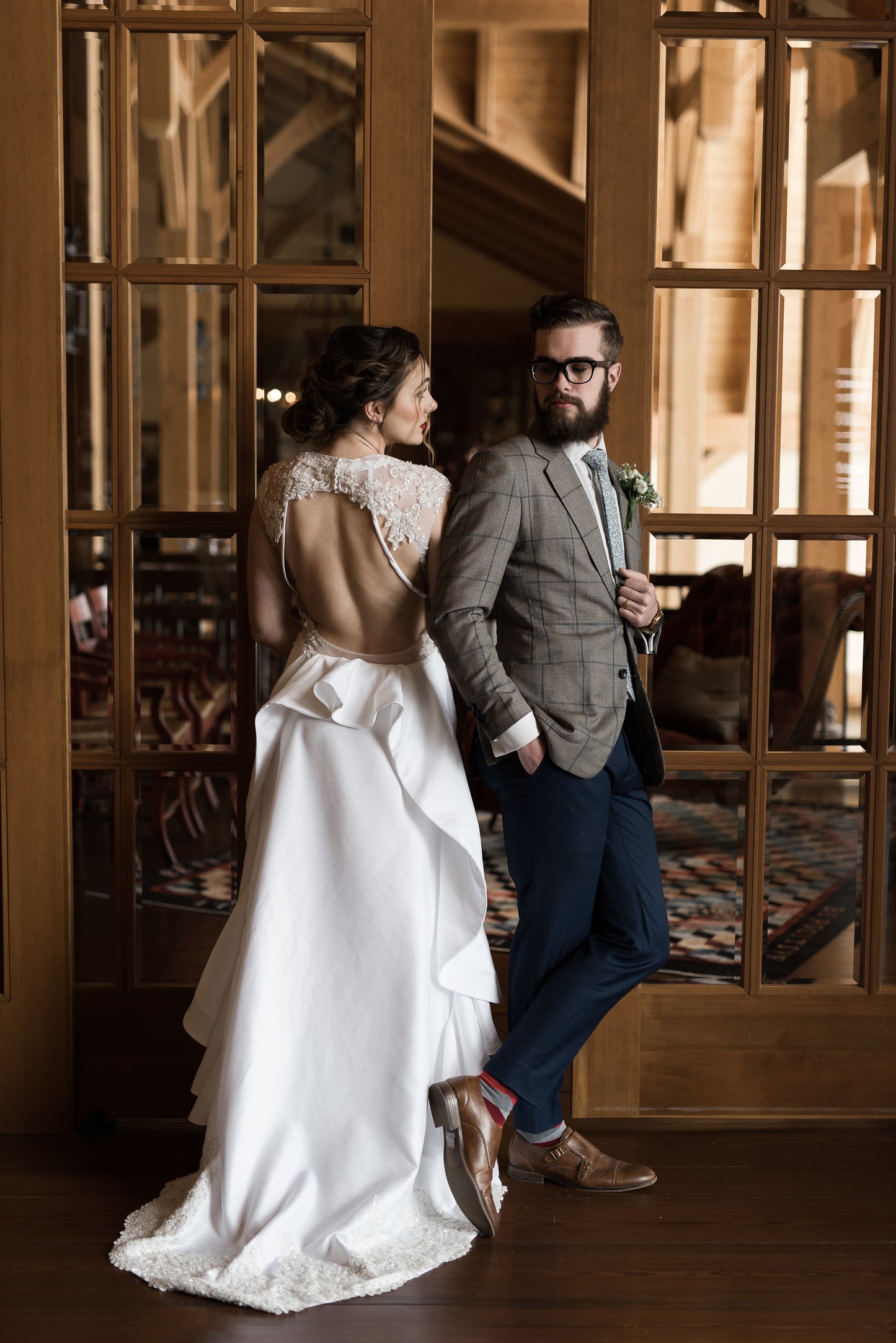 A full back image of the Mia gown, a bride and groom stand together, while the mia gown has the train spread out toward the camera with the keyhole detail and beaded lace just above. 