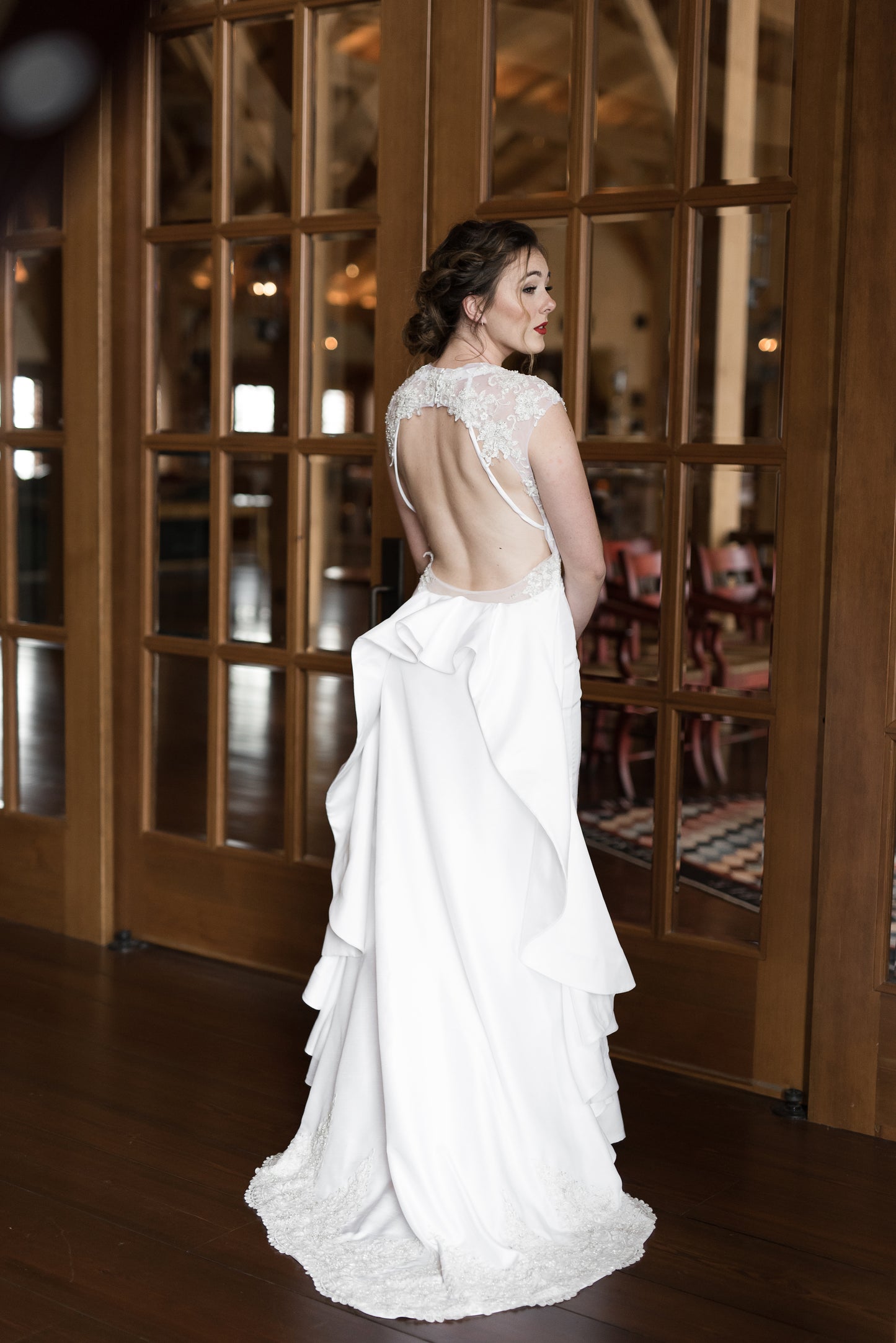 A full length shot of the back of the mia wedding gown with a keyhole back, ruffle train, scalloped lace hem and vintage flare. 