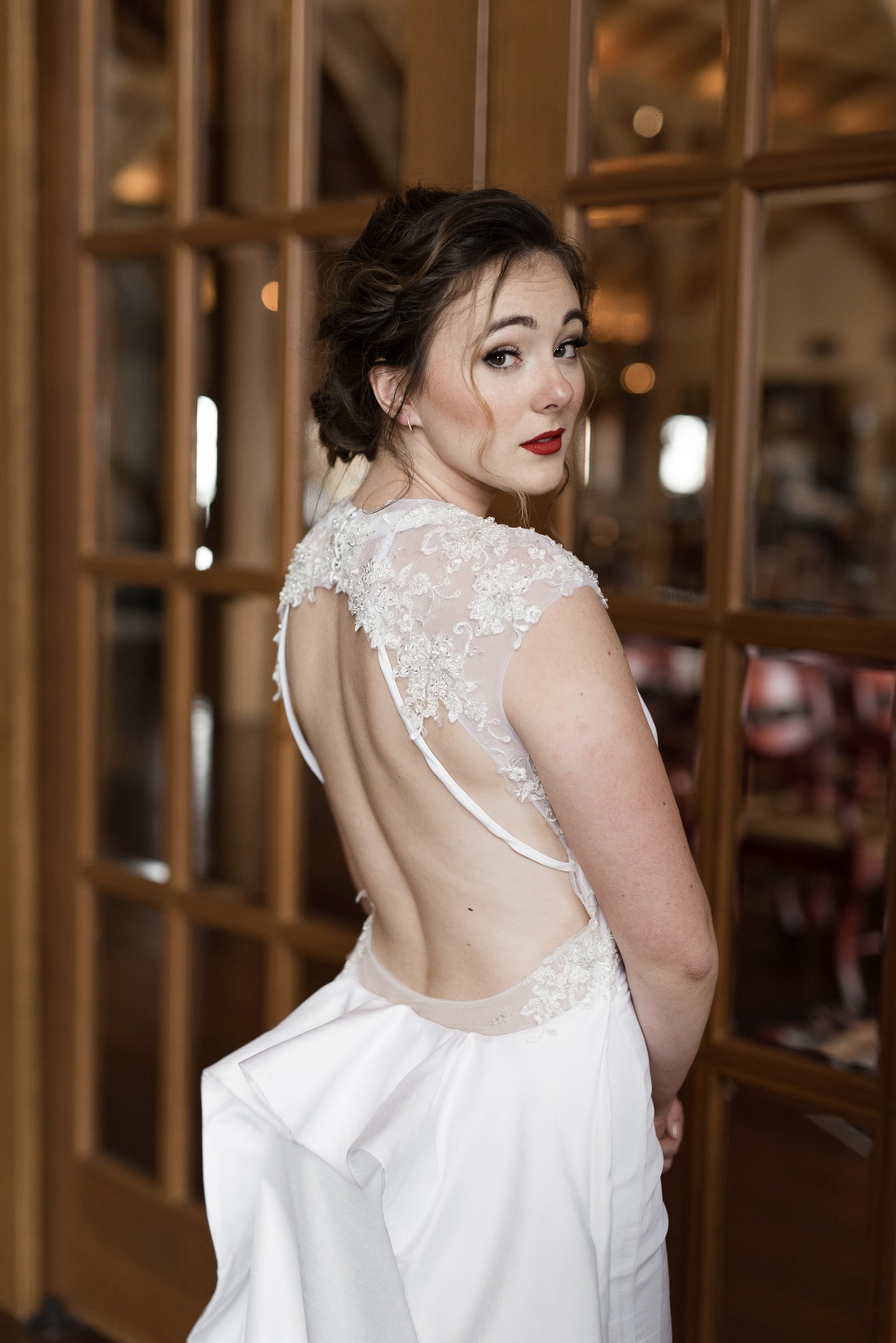 Bride wears the Mia gown and shows off the back of the dress at an angle; the Tulle back bodice with large keyhole framed in lace and satin straps.