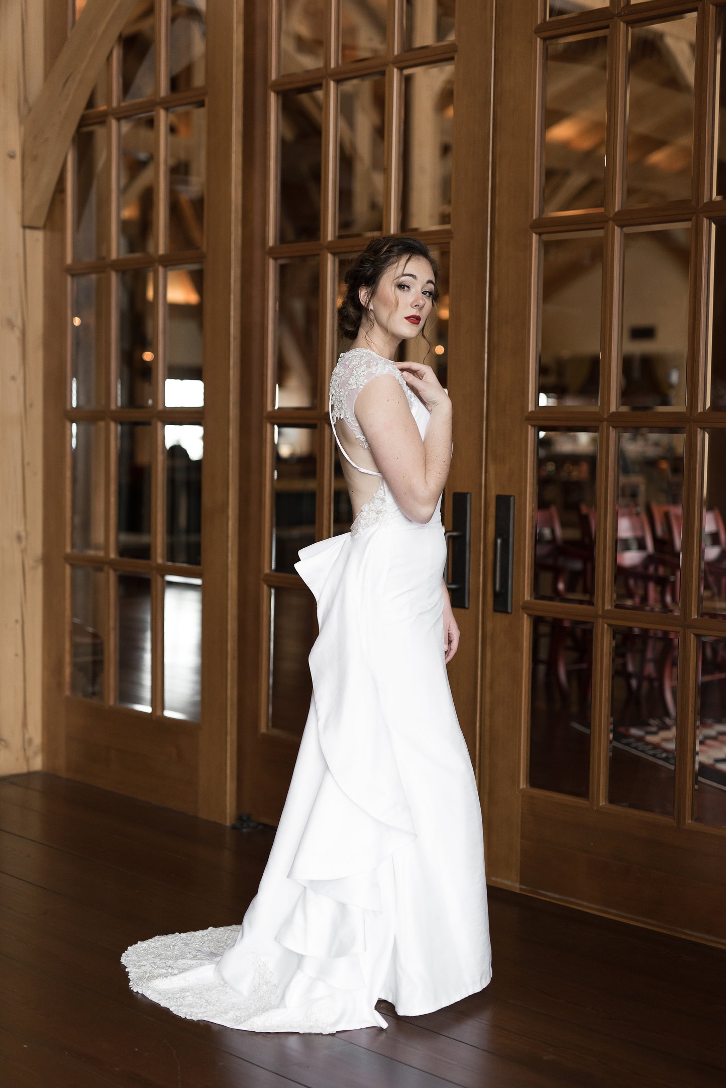 A side portrait of a bride wearing the mia gown; The keyhole tulle back bodice spreads wide enough you can easily see the edge while the ruffle on the train gives an emphasis to the curves and shows some movement. 