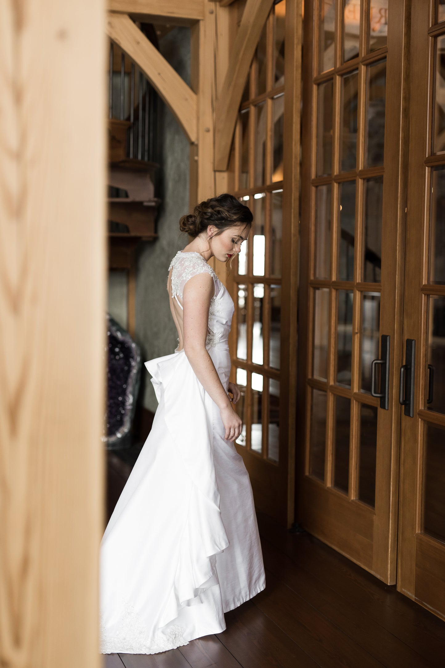 A side view of a bride wearing Mia; she walks forward and you can see the sheath trumpet combo silhouette with ruffle train. 