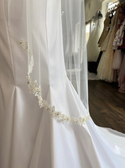 A profile shot of the calf length bridal veil, Haven, and the beaded trim along the hem. The gown has been paired with a satin mermaid gown. 