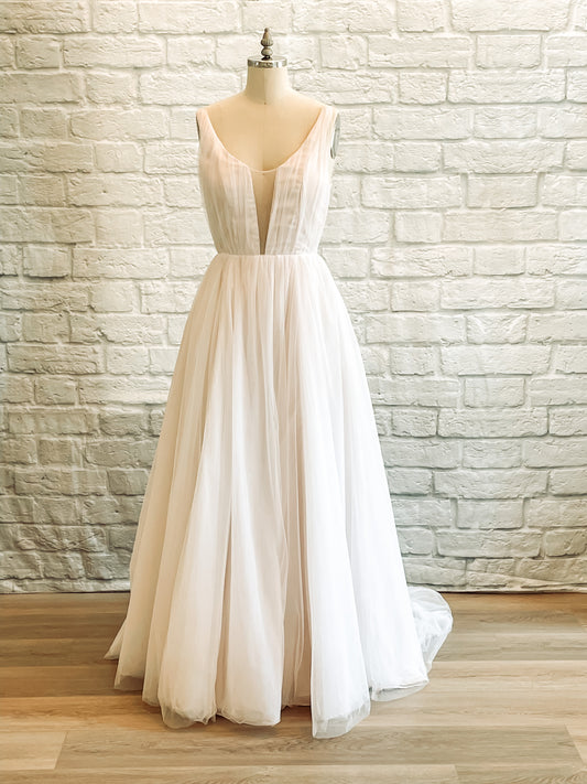 Full front of the Persephone wedding gown on a mannequin, with a scoop neckline, illusion plunge, and full tulle skirt.