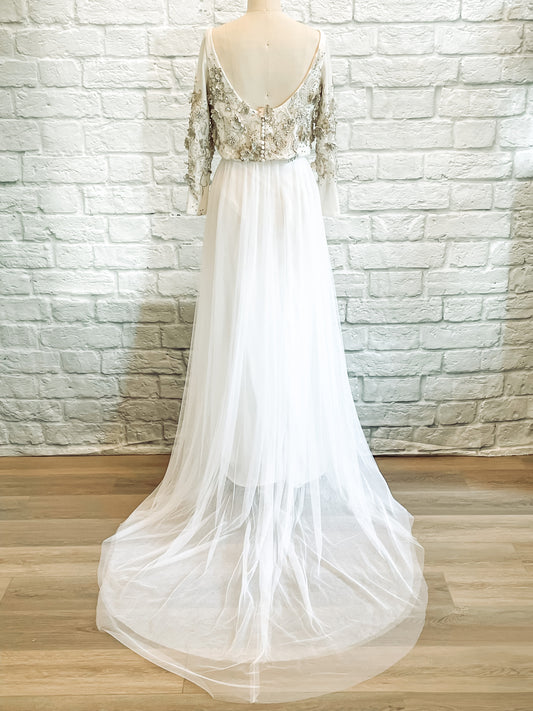 Back view of the gown showing scoop-back bodice, satin-covered buttons, and soft train.