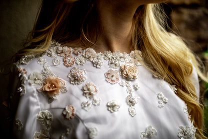 a detail shot of the lydia gowns neckline, showing the front boat neck with the irregular lace placement, natural edge and lace details. 