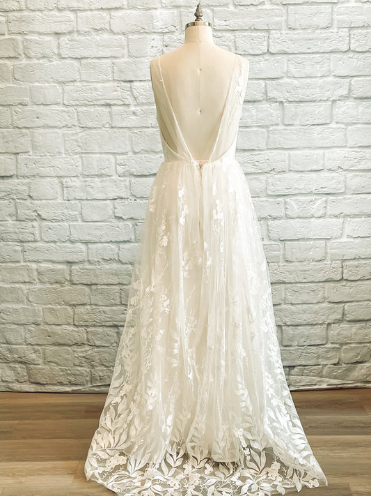 Full back view of the Rosie wedding gown on a mannequin with a Lace-only back bodice, sequin detailing and delicate train.