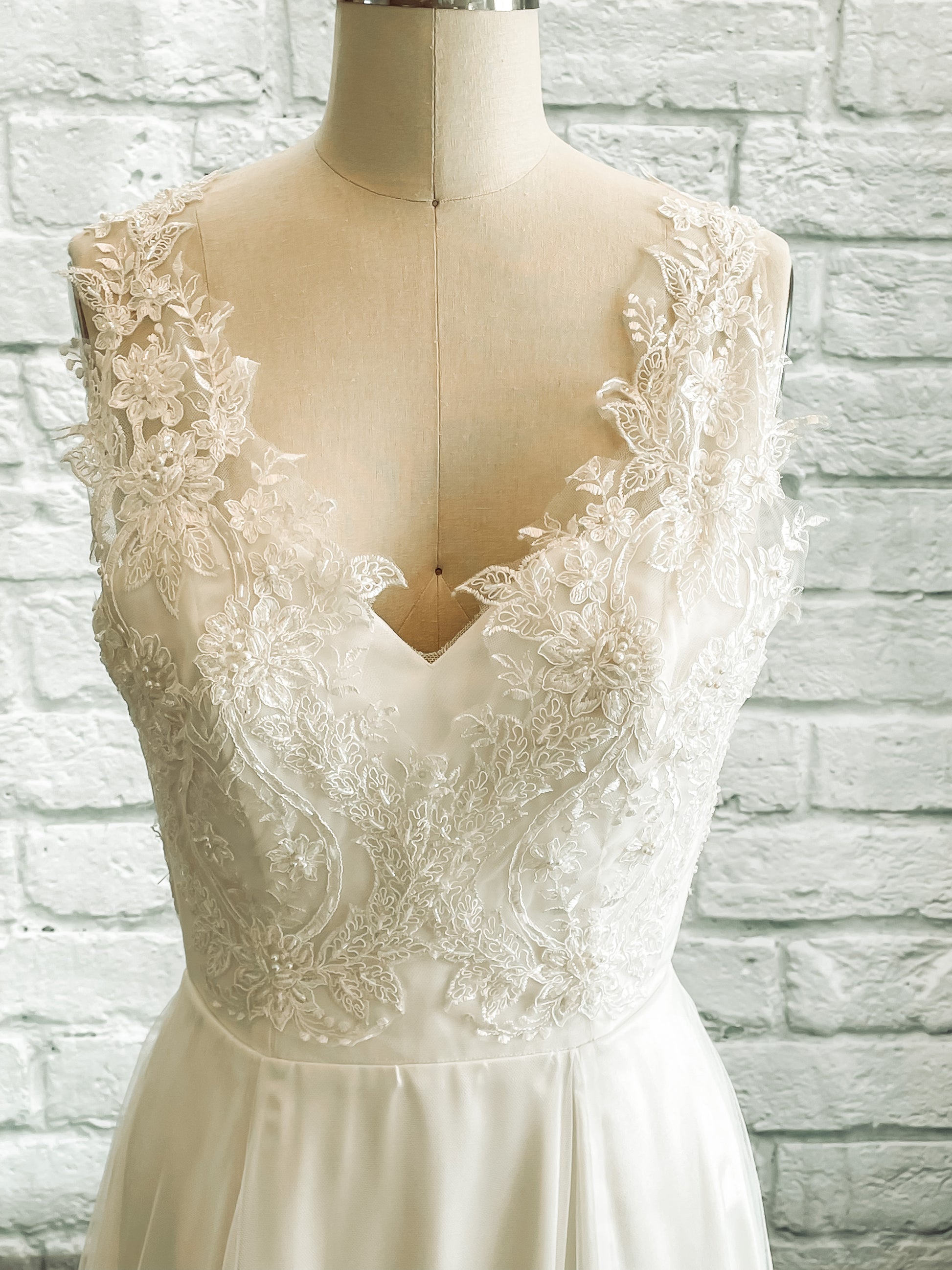 A close up of the front bodice with Hand-cut lace on illusion tank over satin bodice with a sweetheart neckline.