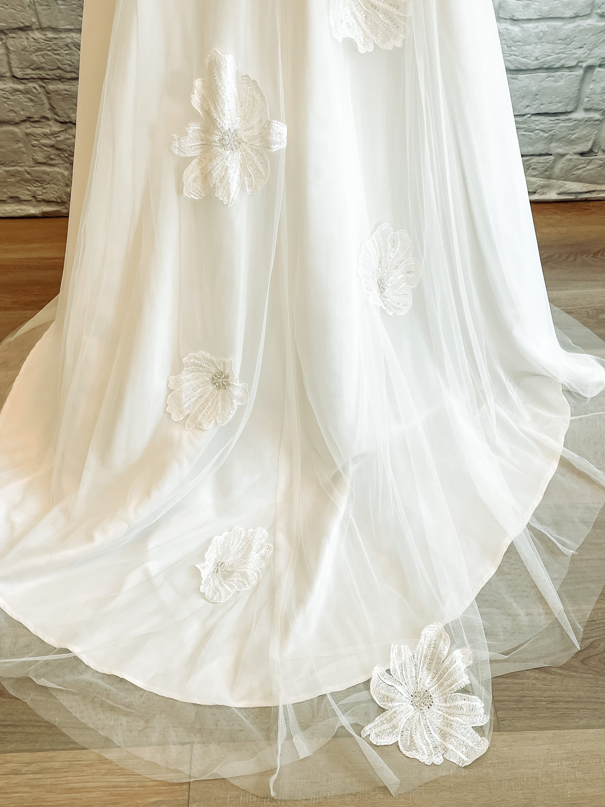 Up close shot of the tulle skirt and train; Three-layers of soft tulle cover the satin train with floral lace cascading down center back