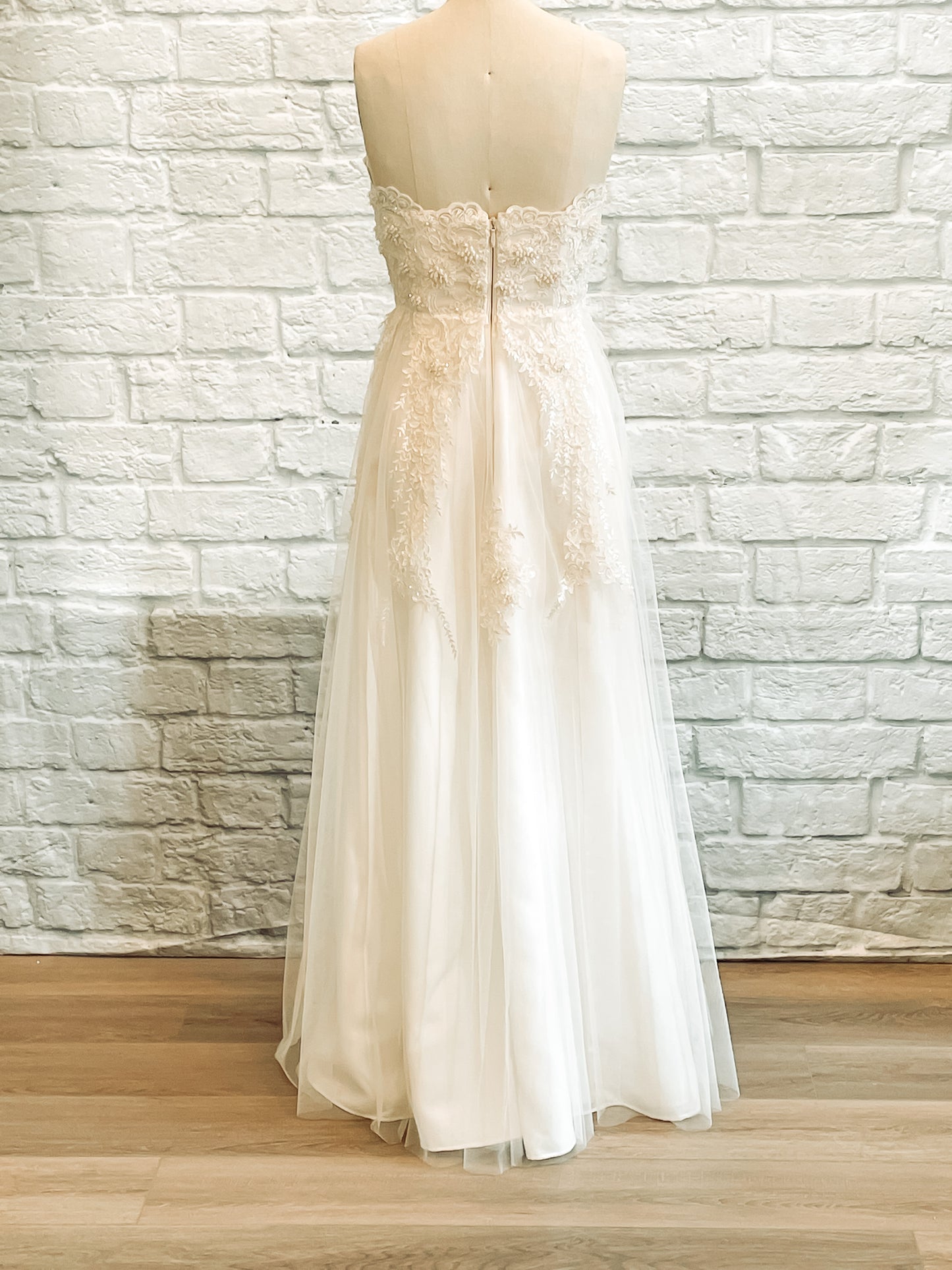 Full back view of the kennsington gown without a train. It features the trickling fading lace pattern, beaded bodice and scalloped neckline edge. 