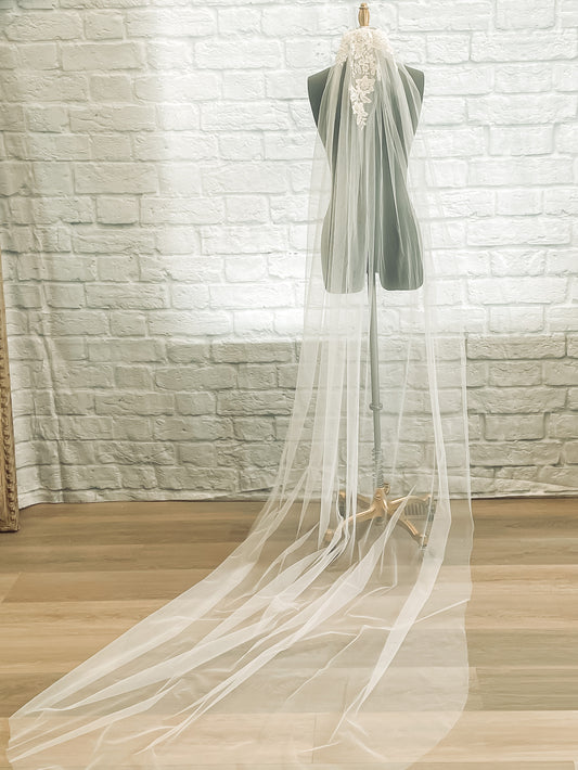A full length photo of the romantic tulle veil sharon veil displayed on a mannequin in a chapel length with floral beaded lace. 